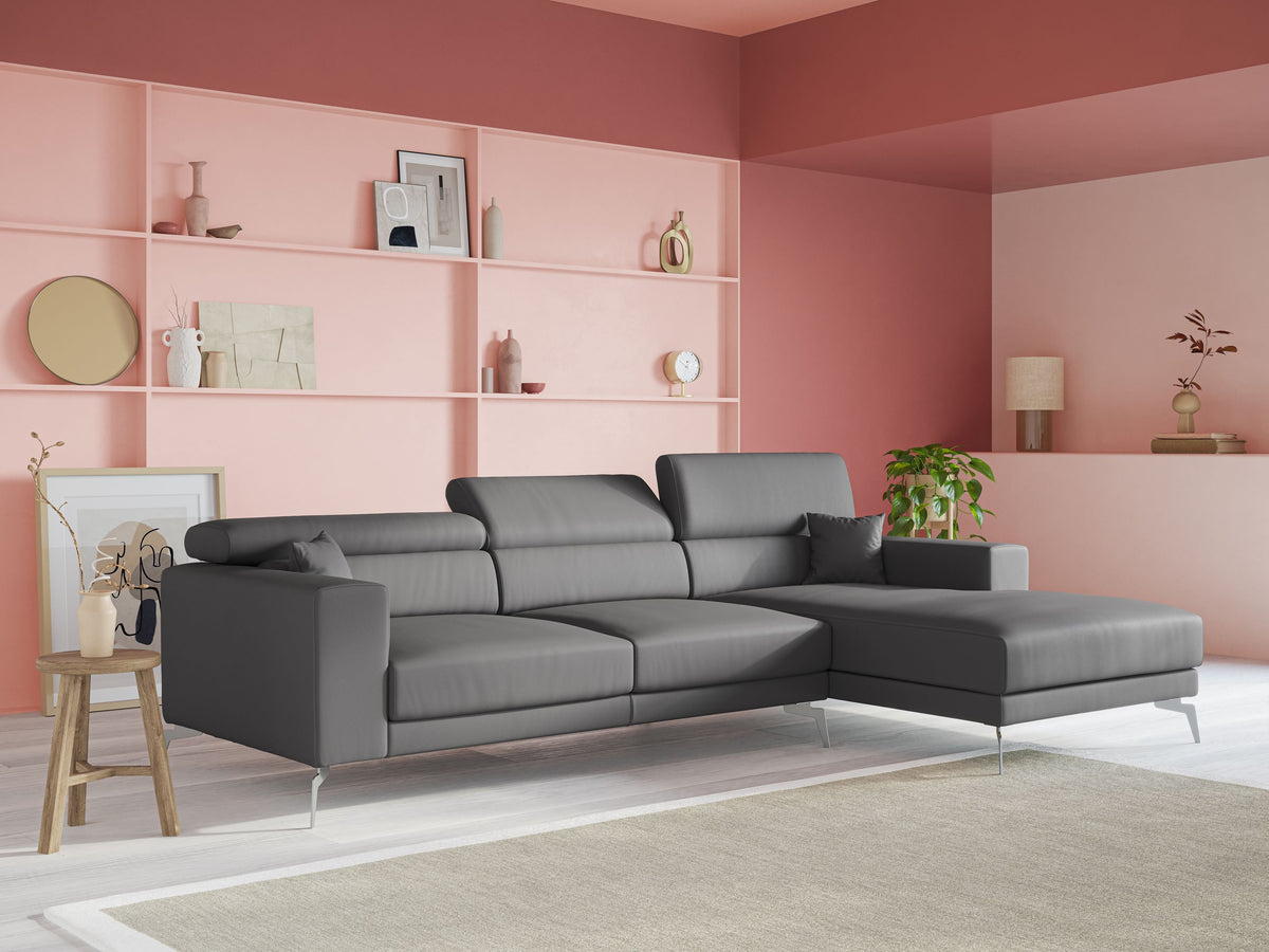 Un soggiorno moderno con un divano in pelle marrone, due cuscini decorativi testurizzati, una lampada da terra nera, un pouf, un arazzo intrecciato e un tappeto chiaro a fantasia su un pavimento in legno.