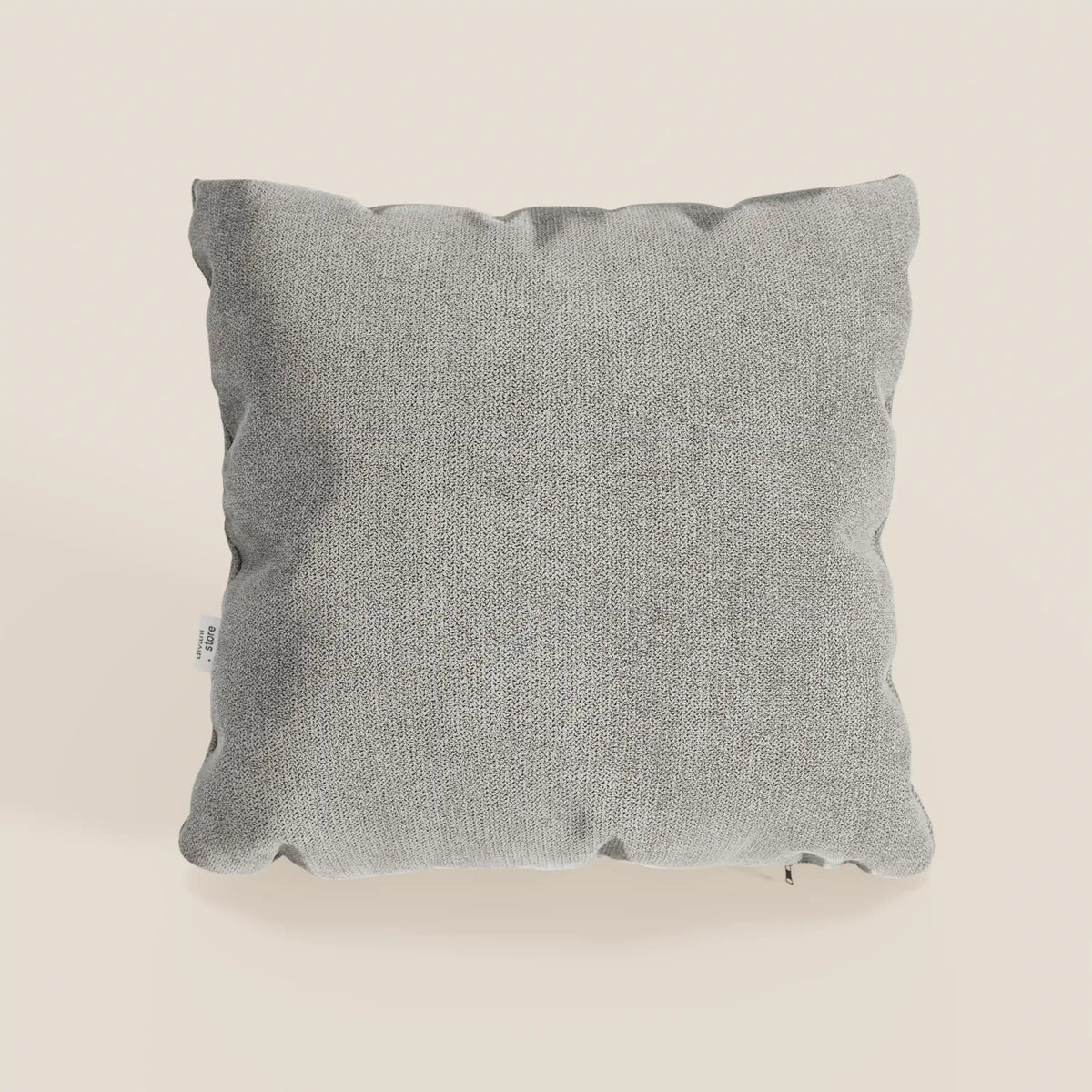 Il cuscino Destiny di divitt.sbs, misura 45x45 cm in morbido tessuto impermeabile T02 beige, è presentato con un aspetto leggermente soffice e una piccola etichetta bianca sulla cucitura sinistra su uno sfondo bianco sporco.