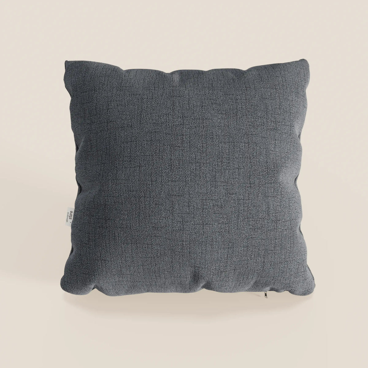Il cuscino Felis cuscino Impermeabile T03 grigio di divitt.sbs è un cuscino quadrato di colore grigio scuro in tessuto morbido e testurizzato con cuciture a vista e etichetta di manutenzione bianca, che offre un comfort resistente all'acqua su qualsiasi sfondo.