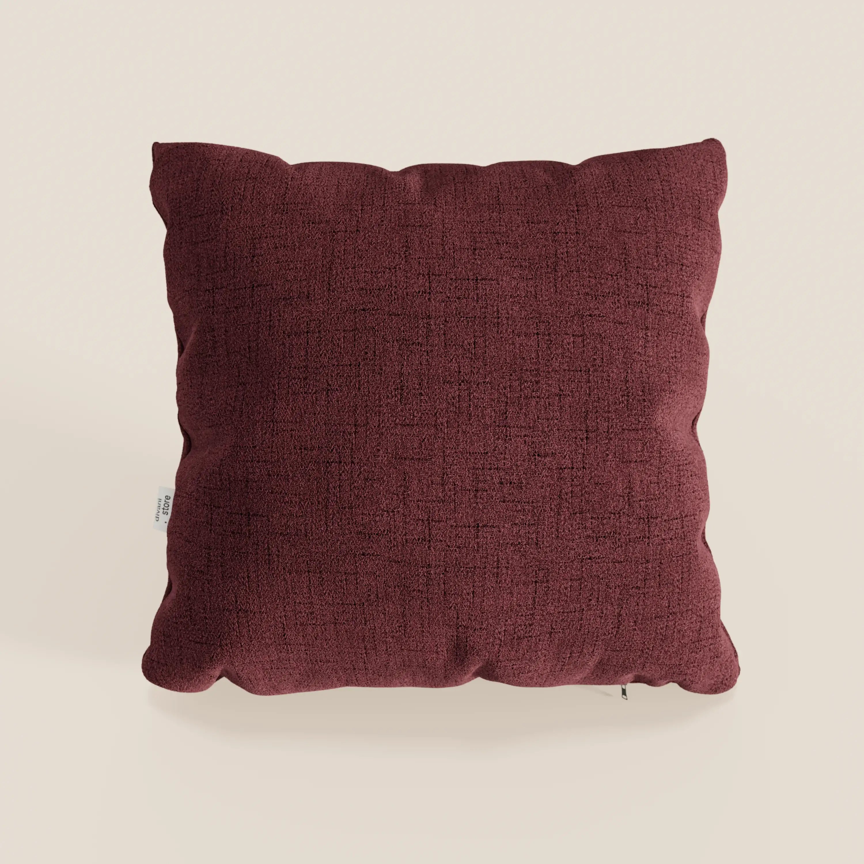 Il cuscino Felis di divitt.sbs in rosso T03 è un cuscino quadrato, marrone, impermeabile, con tessuto morbido, superficie strutturata, design minimalista, angoli arrotondati, cuciture a vista e una piccola etichetta bianca sul lato sinistro su sfondo beige.