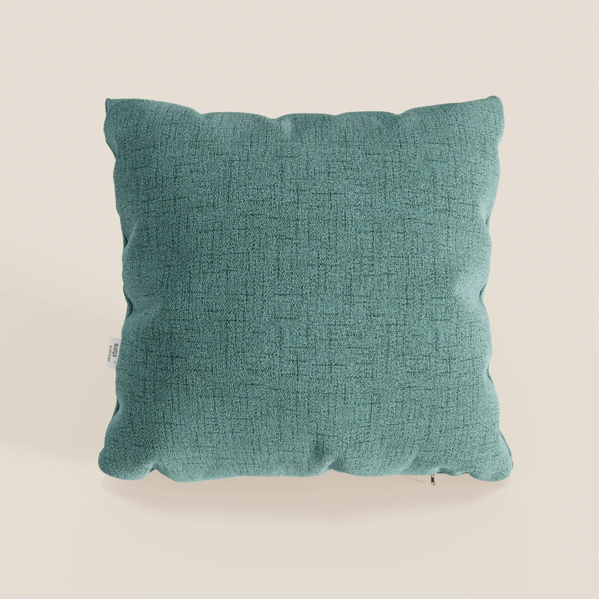 Il cuscino Felis di divitt.sbs, 45x45 cm in verde acqua T03, è caratterizzato da una forma squadrata in morbido tessuto idrorepellente con una sottile trama e bordi frastagliati, su uno sfondo crema chiaro con etichetta laterale bianca.