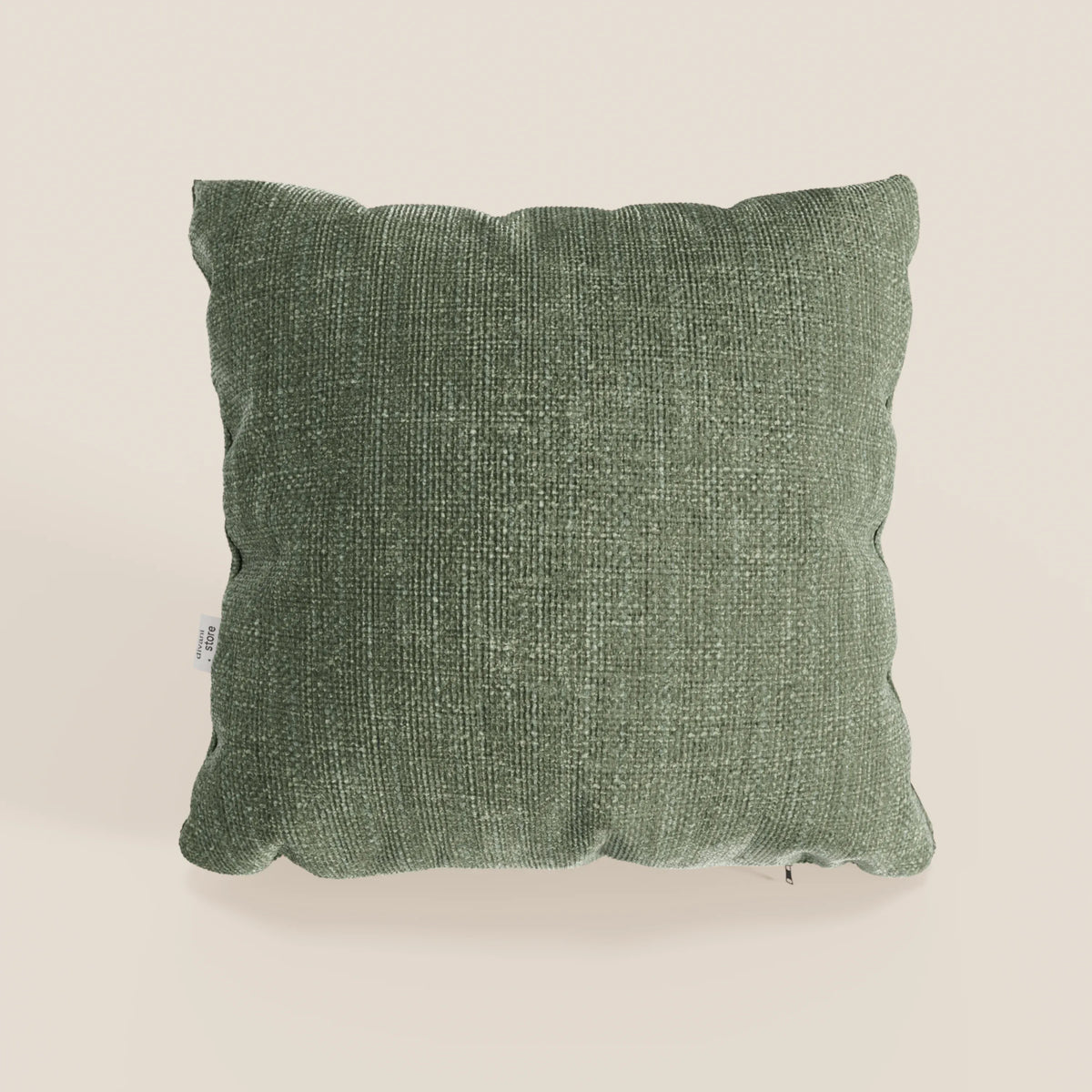 Il cuscino Lyon di divitt.sbs, presentato nel colore verde testurizzato T06 (45x45 cm), è realizzato in morbido tessuto impermeabile con angoli arrotondati e una targhetta bianca sul lato sinistro, su uno sfondo beige chiaro.