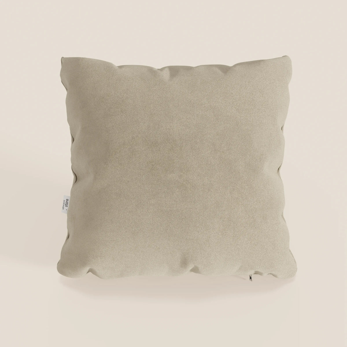 Il cuscino Jazz di divitt.sbs in T11 beige, 45x45 cm, è caratterizzato da un morbido rivestimento in microfibra tecnica antimacchia. Presentato su uno sfondo a tinta unita, ha un aspetto felpato con bordi leggermente gonfi e una piccola etichetta sul lato sinistro.