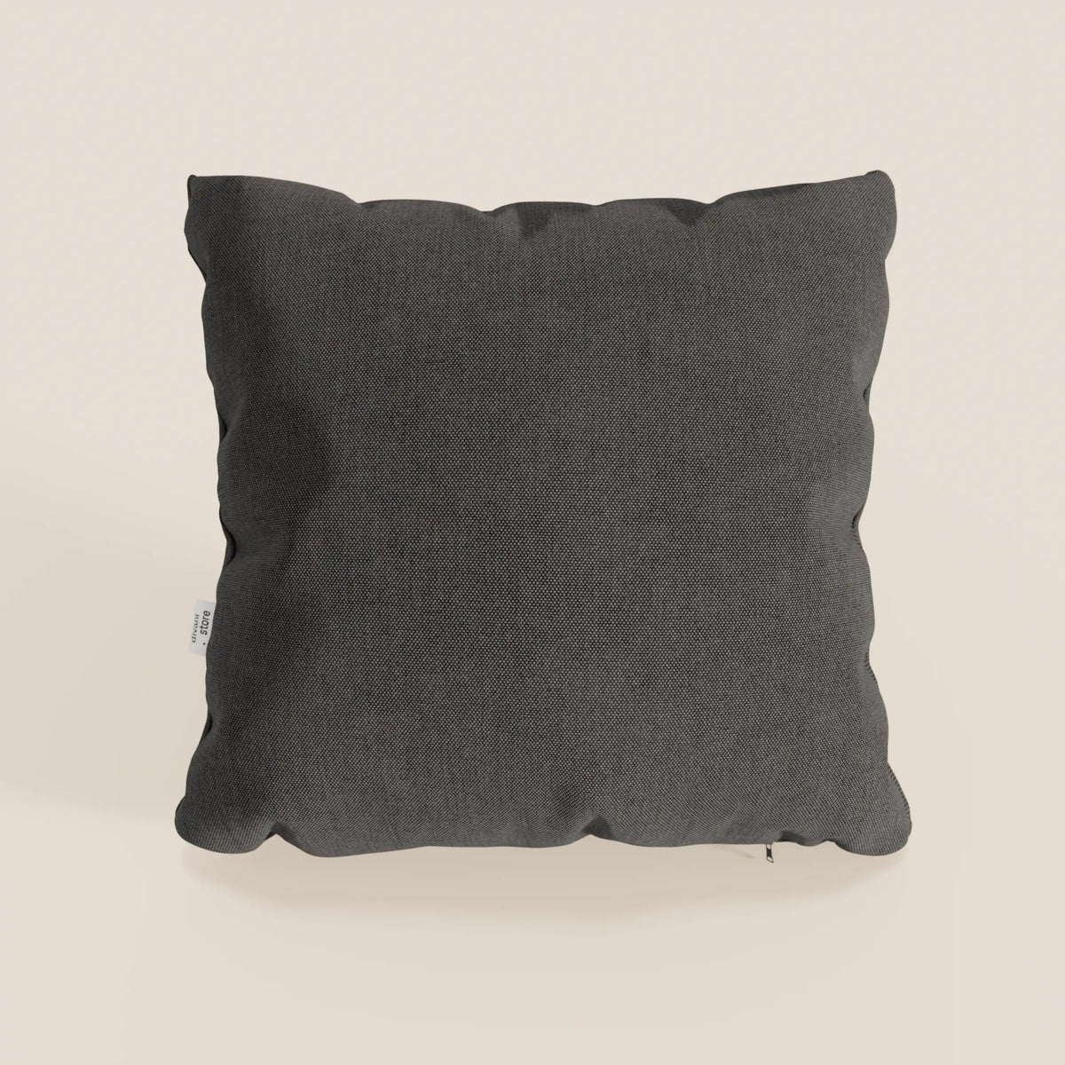 Il cuscino Honey 45x45 di divitt.sbs, in T13 antracite tessuto simil cotone impermeabile, è presentato su un fondo beige chiaro con bordi leggermente frastagliati, etichetta a vista e morbide ombreggiature.