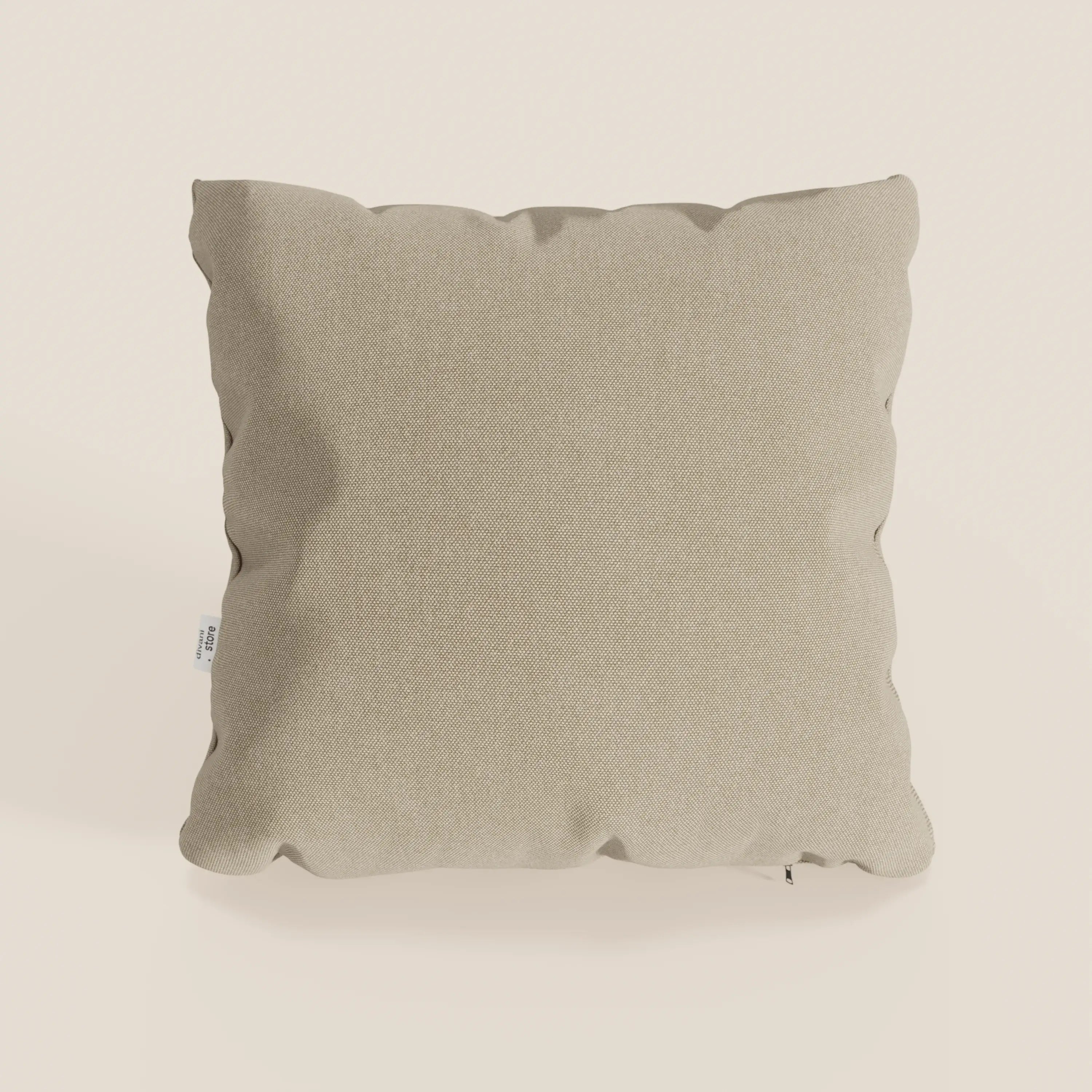 Il cuscino Honey di divitt.sbs, presentato in beige, è caratterizzato da un design quadrato in tessuto impermeabile T13 simile al cotone con una texture sottile. Bordi leggermente arrotondati, aspetto morbido e una piccola etichetta bianca sulla sinistra. Fodera 45x45 inclusa.
