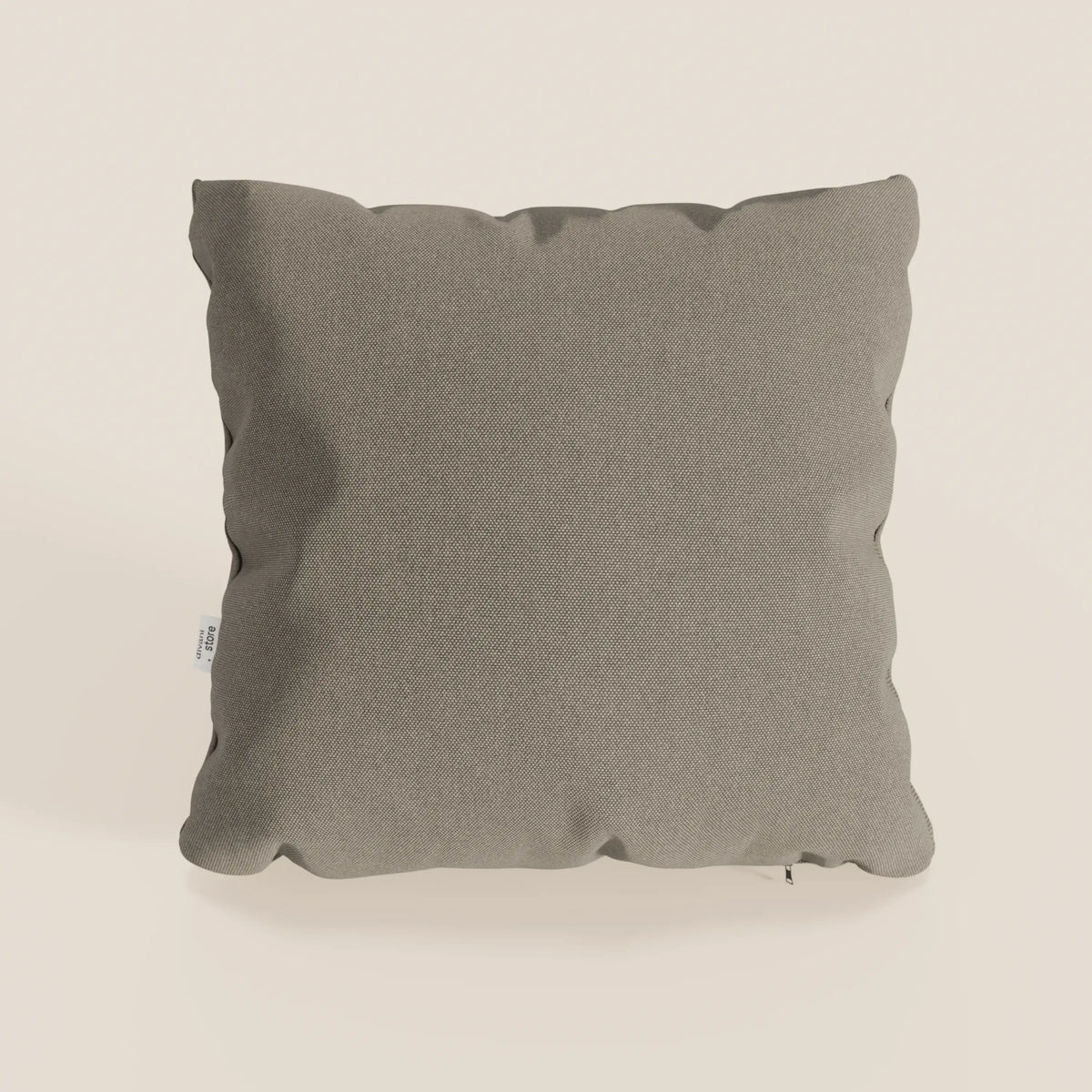 Un cuscino Honey grigio chiaro quadrato 45x45 cm di divitt.sbs in tessuto simil cotone impermeabile T13 tortora con bordi leggermente arrotondati e una piccola etichetta bianca si staglia su uno sfondo bianco sporco.