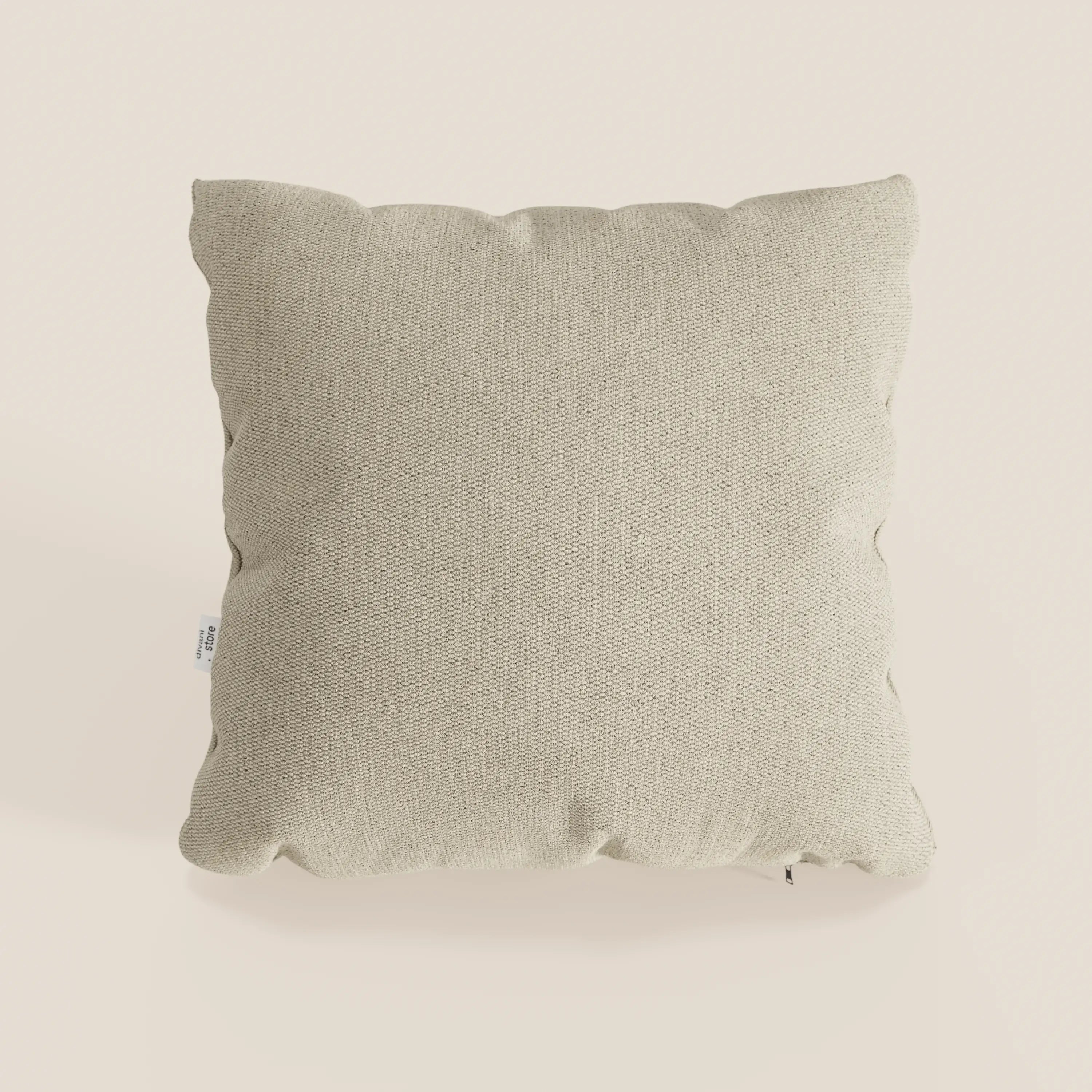 Il cuscino Miami di divitt.sbs, 45x45 cm in T14 beige, è caratterizzato da un morbido tessuto impermeabile, angoli delicatamente arrotondati e una discreta etichetta laterale bianca. Il cuscino, dal design semplice, è posizionato su uno sfondo color crema chiaro.