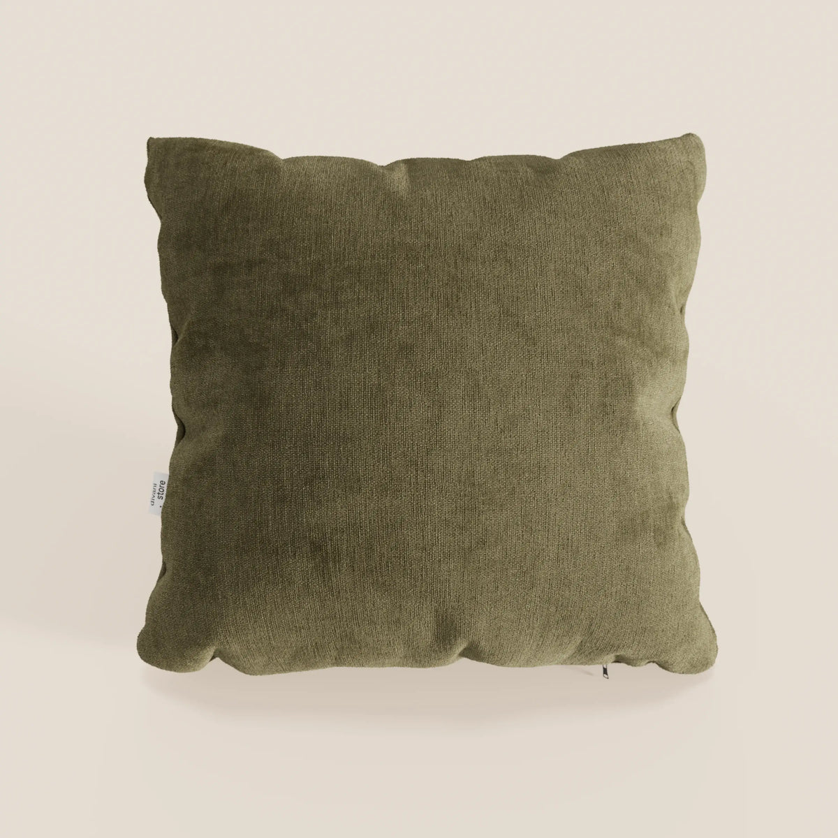 Un cuscino Bolero quadrato verde oliva di divitt.sbs, realizzato in morbido tessuto T31 antimacchia, impermeabile e non restringente, si staglia su un semplice sfondo beige. Gli angoli leggermente arrotondati e una piccola etichetta bianca aggiungono un fascino discreto.