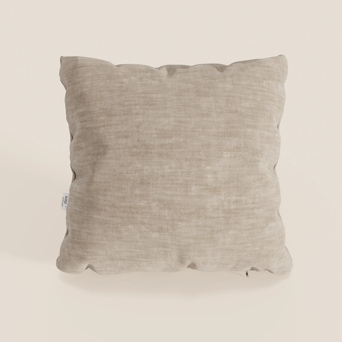 Il cuscino Sofia di divitt.sbs è un cuscino decorativo quadrato di colore beige, realizzato in morbido velluto antimacchia Easy Clean T35. I bordi leggermente arrotondati e l'aspetto felpato lo rendono invitante; una piccola etichetta bianca compare sul lato sinistro.