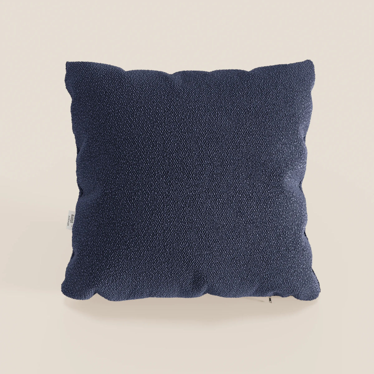 Il cuscino Lambada di divitt.sbs è presentato in blu navy, con un tessuto T33 in fresco cotone naturale, lavabile e impermeabile; una piccola etichetta bianca appare sul lato su uno sfondo beige chiaro.