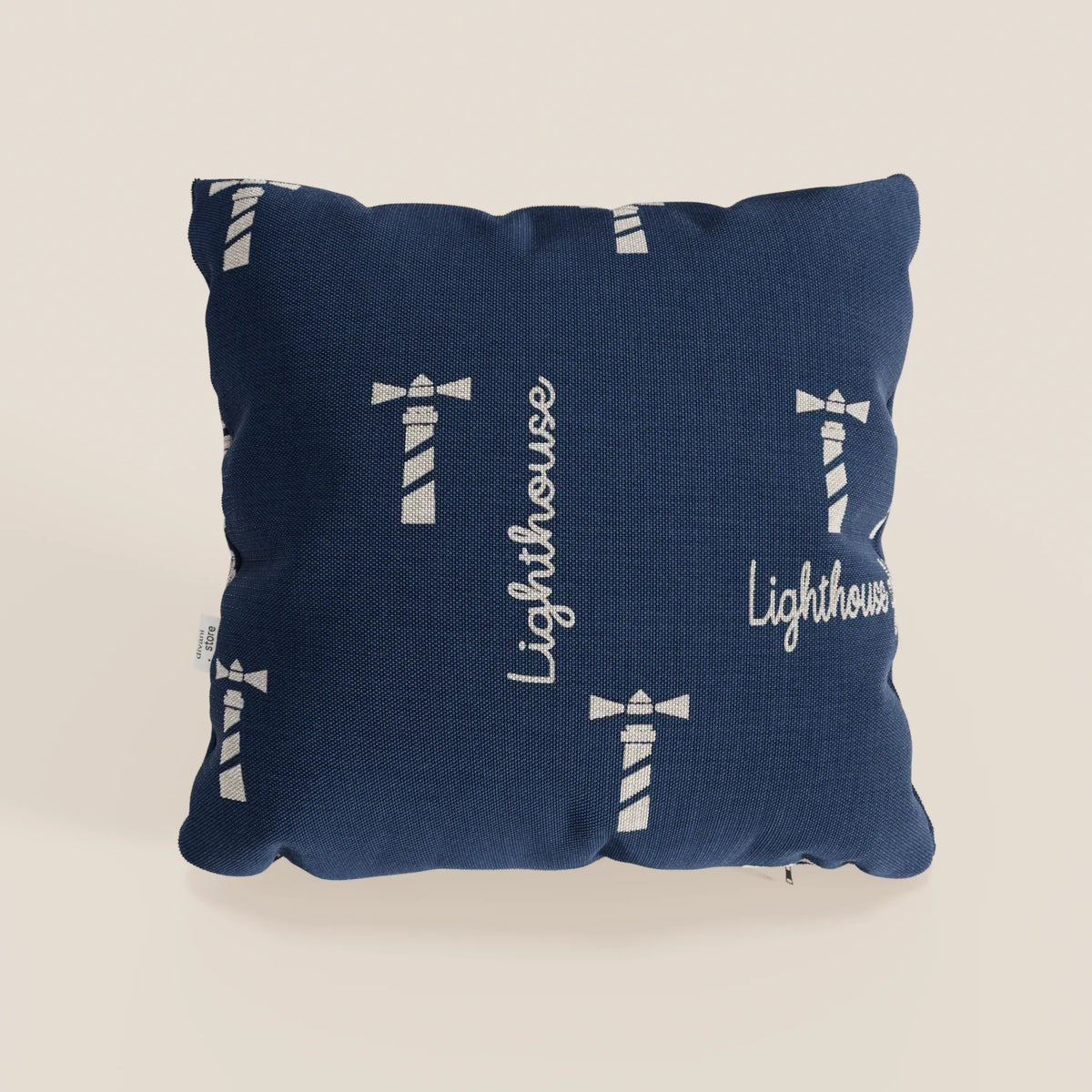 La collezione di cuscini Nautilus di divitt.sbs è caratterizzata da un cuscino quadrato impermeabile di colore blu con grafica bianca del faro e scritta "Lighthouse" in corsivo, perfetto per un arredamento a tema marino elegante e facile da pulire.