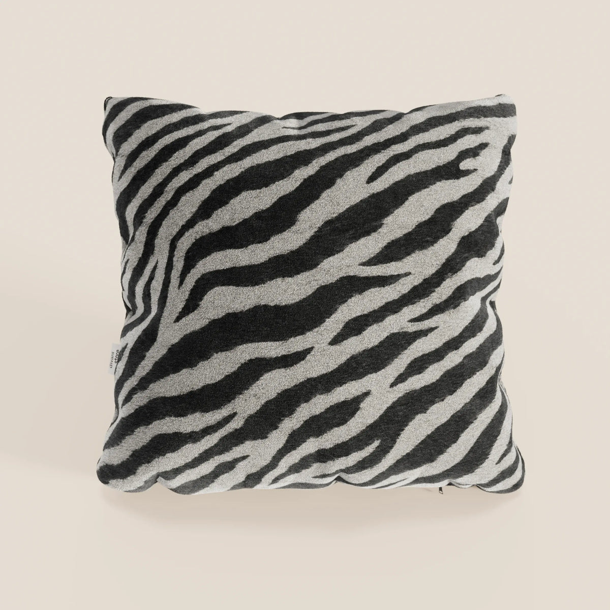 Il cuscino Wild 45x45 di divitt.sbs, della collezione Wild, presenta un motivo zebrato bianco e nero in morbido tessuto microfibra impermeabile, appoggiato su uno sfondo beige chiaro con angoli leggermente arrotondati.