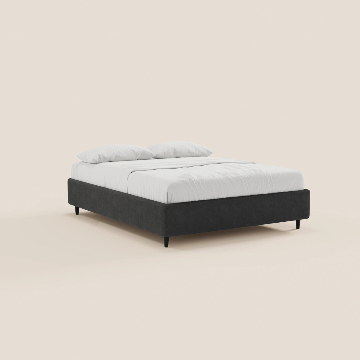 Il letto sommier imbottito ERON di Letti.store presenta una struttura bassa rivestita in tessuto impermeabile certificato Oeko-Tex di colore nero, gambe nere, lenzuolo con angoli bianco, coperta e due cuscini; è raffigurato inclinato verso sinistra su uno sfondo beige chiaro a tinta unita.
