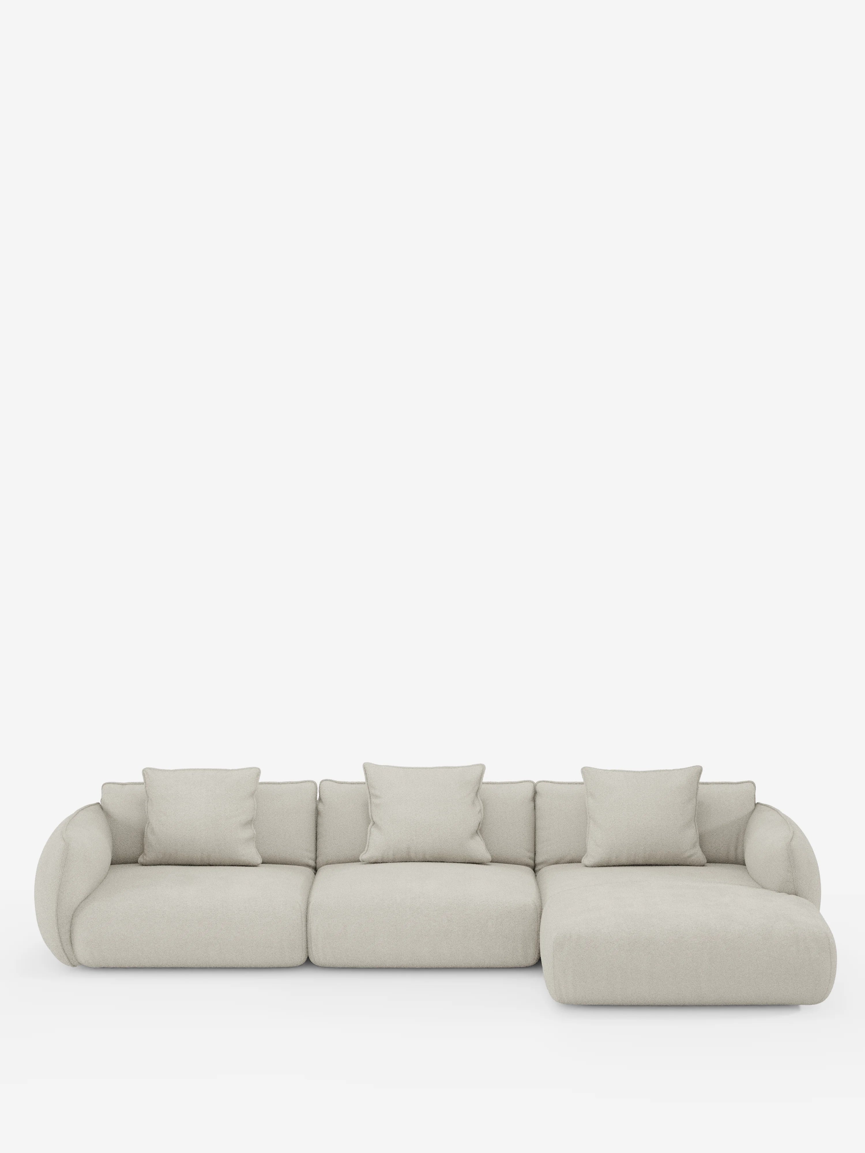 Il divano angolare con penisola componibile Nimbus in morbido tessuto effetto cotone smacchiabile T33 di divitt.sbs è un divano componibile moderno, di colore beige chiaro, con tre posti e una chaise longue sul lato destro. Presenta braccioli arrotondati, morbidi cuscini e tre cuscini quadrati coordinati per lo schienale. Il design elegante di questo divano angolare risalta su uno sfondo bianco a tinta unita.