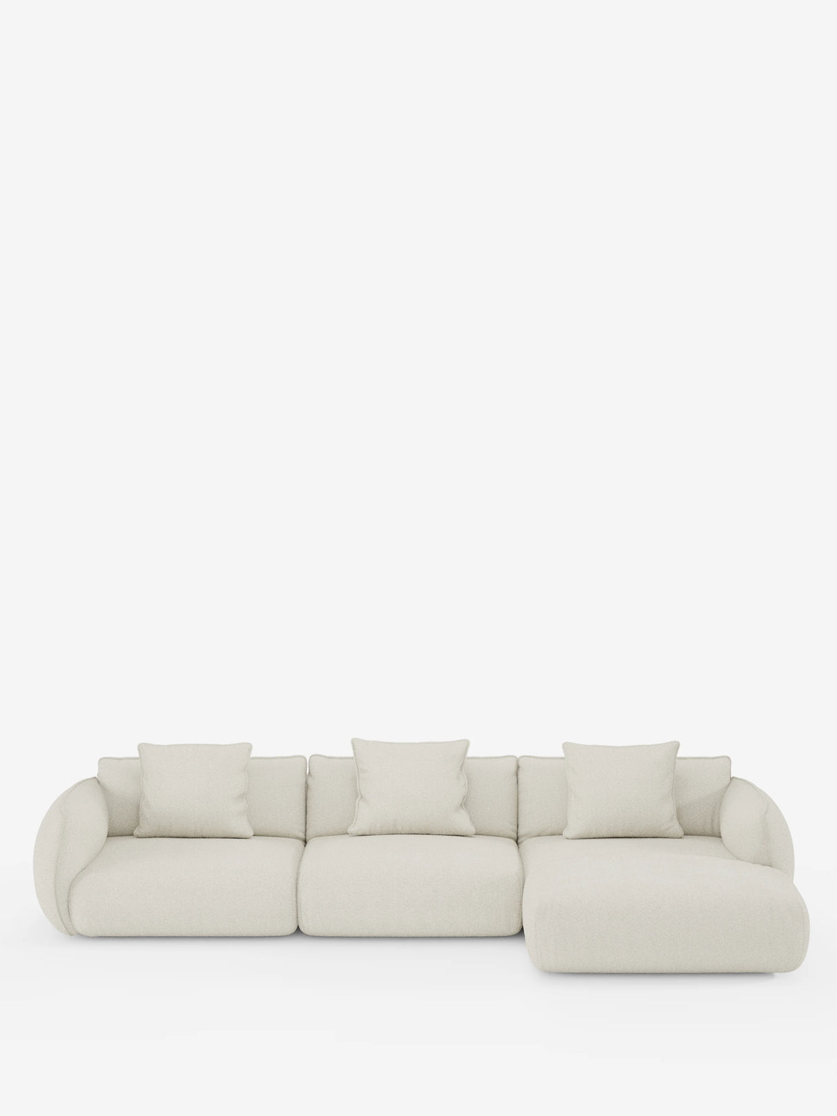 Un divano angolare con penisola componibile Nimbus, dal design contemporaneo e minimalista, firmato divitt.sbs, rivestito in tessuto T33 effetto cotone color beige chiaro, antimacchia. Il divano comprende tre sezioni di seduta, quattro cuscini coordinati e una chaise longue sul lato destro (penisola), il tutto presentato su uno sfondo bianco. I bordi arrotondati e il design morbido creano un'estetica accogliente.