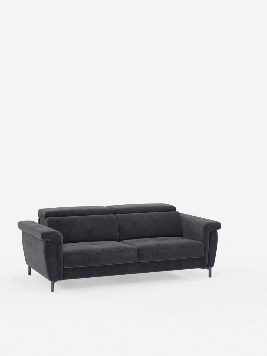 Un divano letto Capri di design contemporaneo, color grigio scuro, realizzato da divitt.sbs, dotato di due cuscini di seduta, due cuscini dello schienale, ampi braccioli e gambe alte e slanciate in metallo nero, con poggiatesta regolabili rivestiti in un elegante tessuto effetto velluto antimacchia (T30), che risalta su uno sfondo bianco a tinta unita.