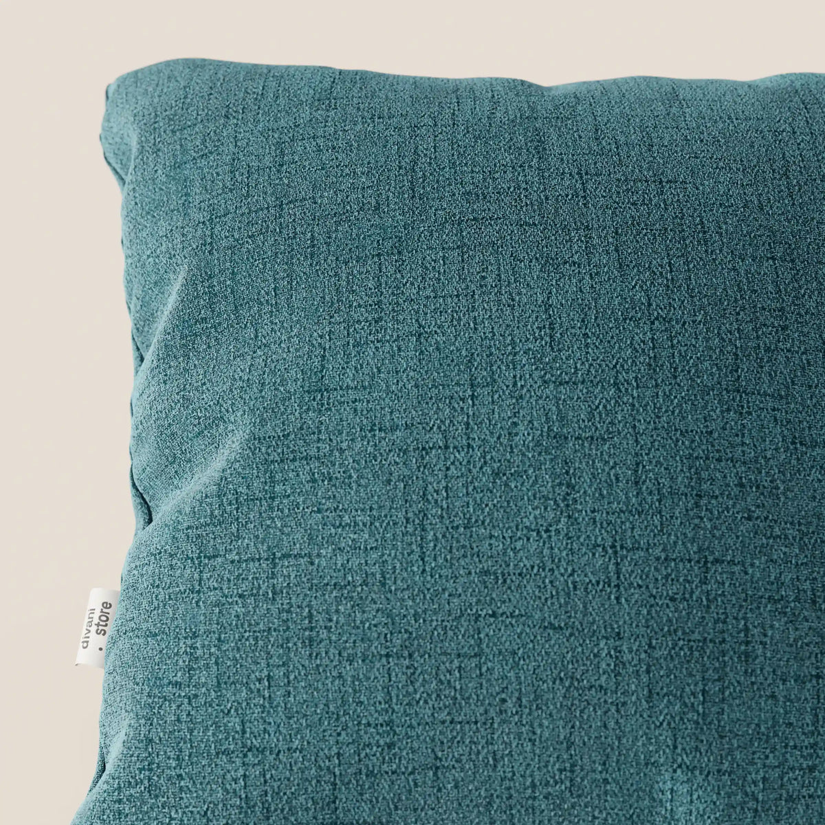 Primo piano dei cuscini Felis di divitt.sbs in azzurro T03, realizzati in morbido tessuto impermeabile con una sottile trama a griglia. L'etichetta "100% cotone" compare sulla sinistra, su uno sfondo neutro e chiaro.