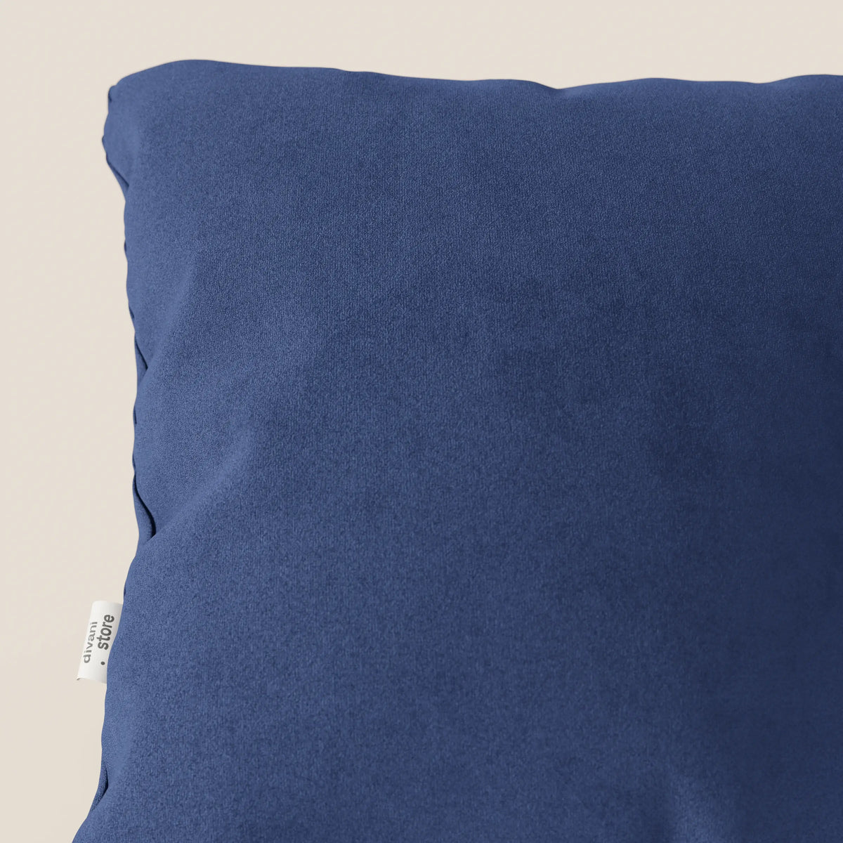 Primo piano del cuscino Jazz di divitt.sbs in T11 blu, un cuscino quadrato di colore blu scuro in microfibra tecnica antimacchia, presentato su uno sfondo beige chiaro con una piccola etichetta in tessuto bianco cucita nella cucitura sinistra.