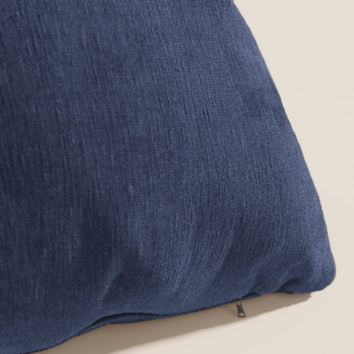 Primo piano del cuscino Bolero di divitt.sbs in blu navy, caratterizzato da un morbido tessuto T31 antimacchia, impermeabile e termoretraibile. La trama fine e il piccolo tiretto della cerniera sul bordo inferiore sono visibili su uno sfondo chiaro.
