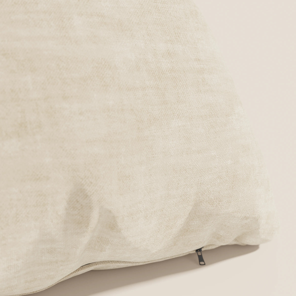 Primo piano del cuscino Sofia di divitt.sbs in beige chiaro, caratterizzato da pieghe morbide, una piccola cerniera nera e realizzato in velluto nuvolato Easy Clean T35 smacchiabile e impermeabile per un look neutro e rilassante.