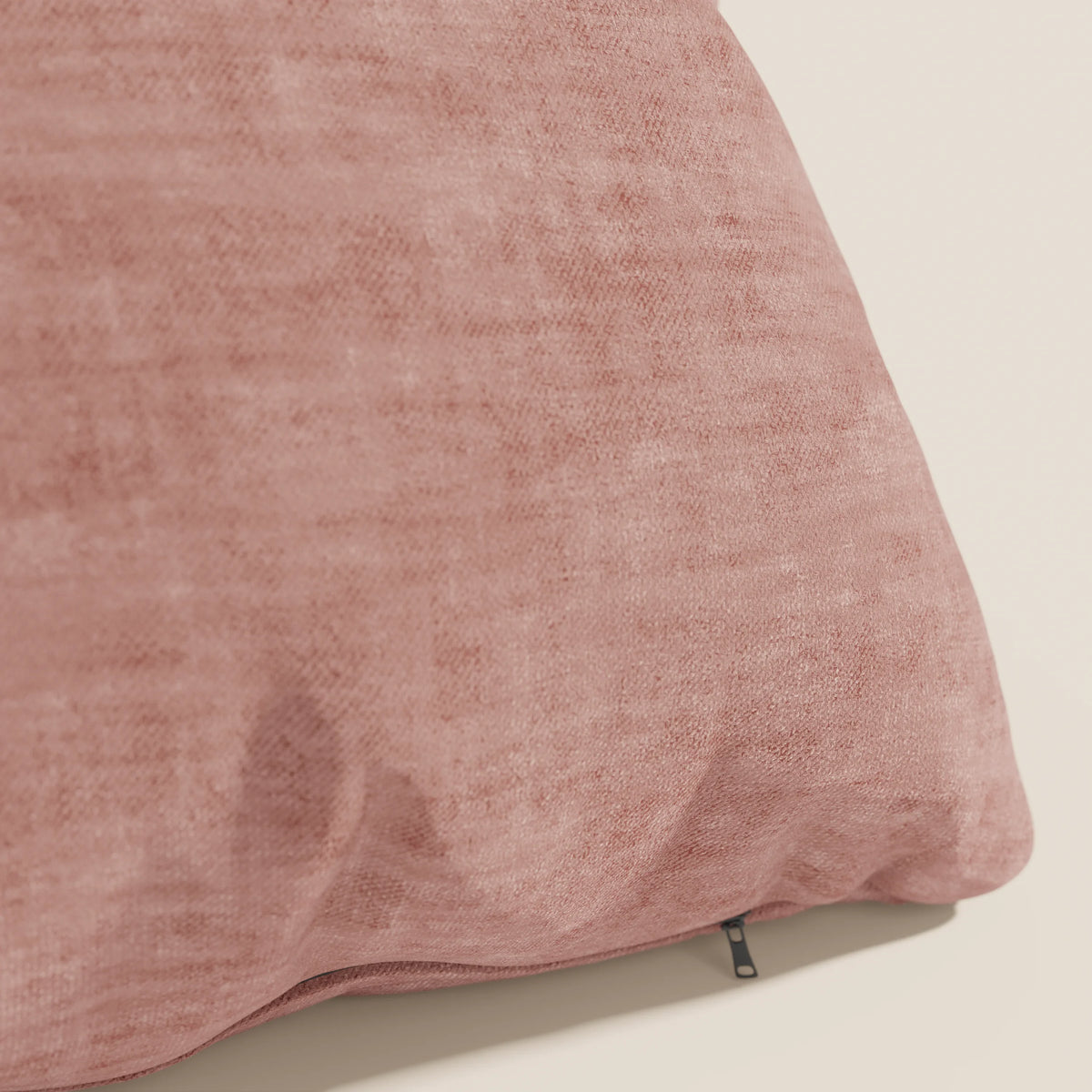 Primo piano di un cuscino Sofia rosa di divitt.sbs in morbido velluto nuvolato (Easy Clean T35), resistente alle macchie e all'acqua, con una cerniera a vista. Il cuscino poggia su una superficie chiara su uno sfondo bianco sporco.