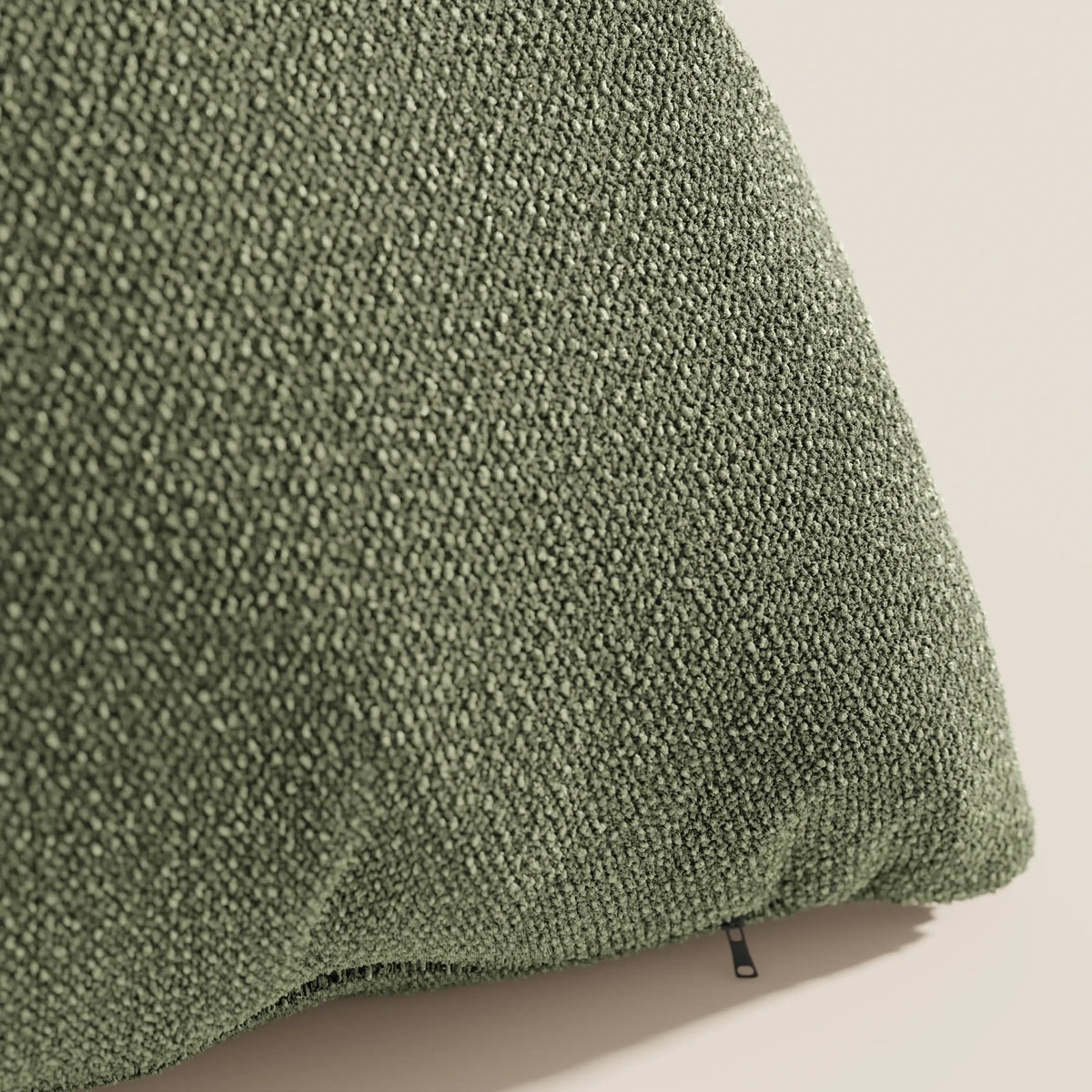 Primo piano del cuscino Lambada verde di divitt.sbs, realizzato in tessuto T33 fresco, lavabile e impermeabile, dalla consistenza simile al cotone. La cerniera visibile è nell'angolo inferiore su uno sfondo chiaro e neutro.