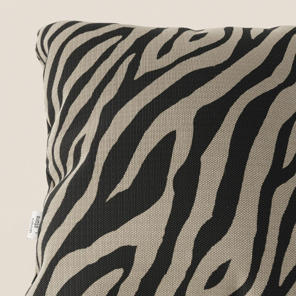 Primo piano di Stripe cuscini geometrici 45x45 di divitt.sbs in tessuto idrorepellente color tortora, caratterizzato da un motivo elegante e resistente; una targhetta bianca appare sul bordo su uno sfondo neutro chiaro.