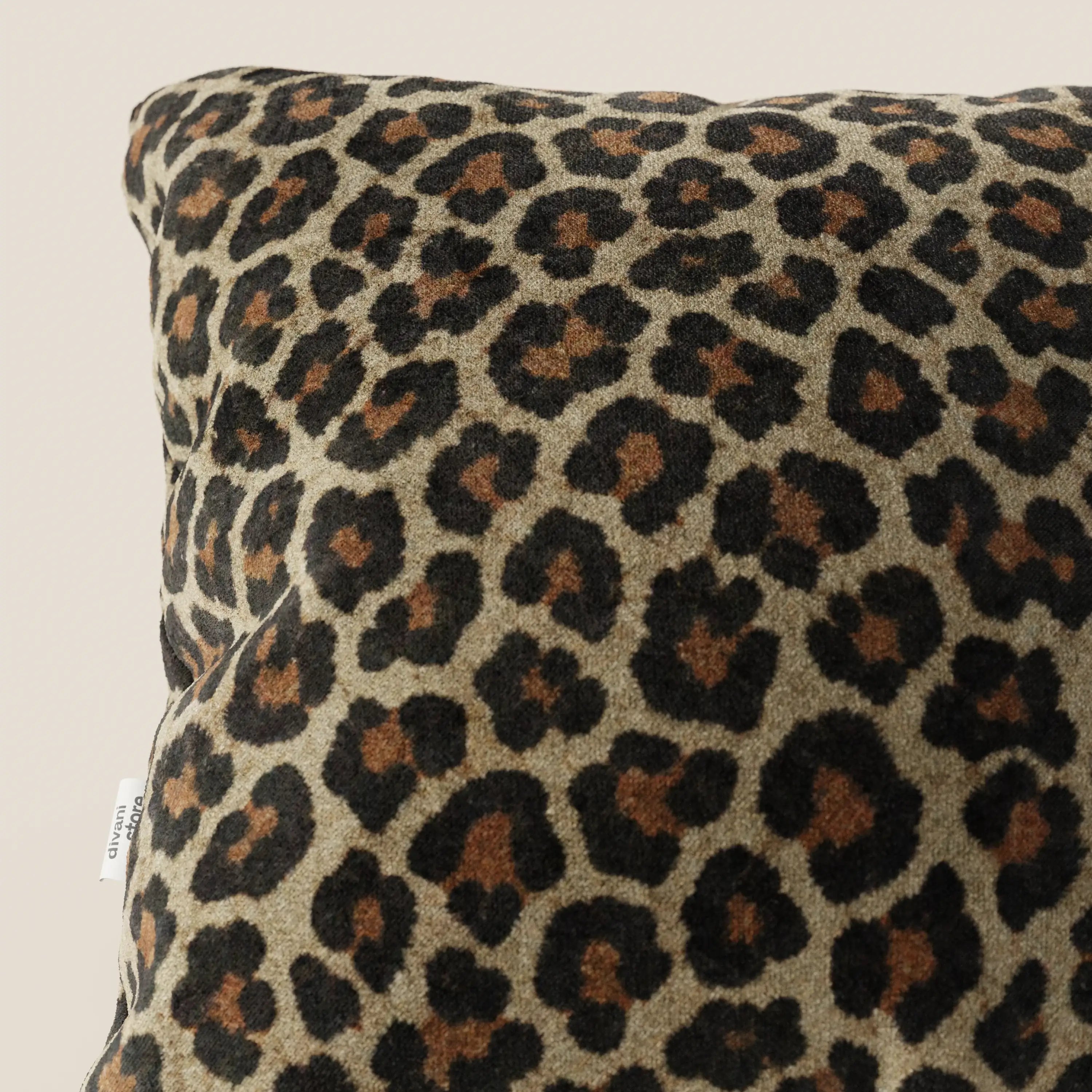 Primo piano del cuscino della collezione Wild in microfibra impermeabile leopardo di divitt.sbs, caratterizzato da una stampa leopardata con macchie nere e marroni su sfondo marrone, una piccola etichetta laterale e uno sfondo neutro.