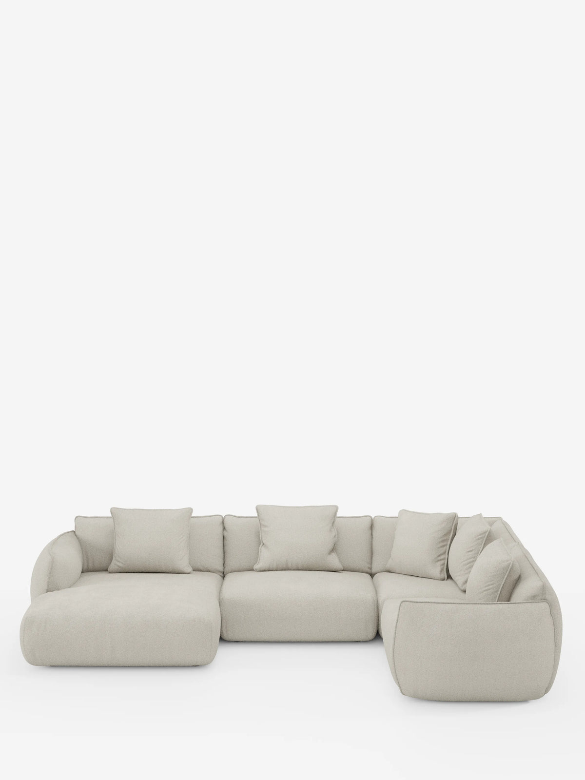 Un divano angolare panoramico componibile Nimbus in beige chiaro, con penisola e angolo in tessuto smacchiabile t33 di divitt.sbs, caratterizzato da un design modulare a forma di L con morbidi cuscini e schienali bassi e arrotondati. Realizzato in Italia, comprende tre sezioni di seduta principali e sette cuscini decorativi coordinati, che risaltano su uno sfondo bianco a tinta unita.