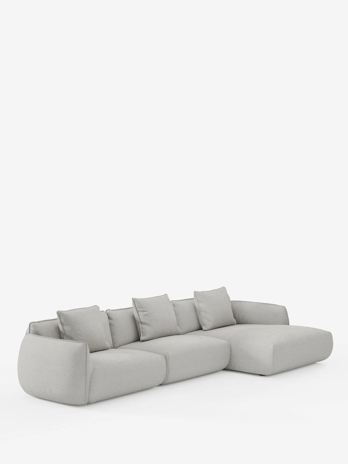 Un moderno divano angolare Nimbus con penisola componibile di divitt.sbs, realizzato in tessuto effetto cotone (T33) di colore grigio chiaro, morbido e resistente alle macchie, dotato di quattro cuscini di seduta e cinque cuscini dello schienale coordinati, con bordi delicatamente arrotondati e una chaise longue estesa sul lato destro, su uno sfondo bianco a tinta unita.