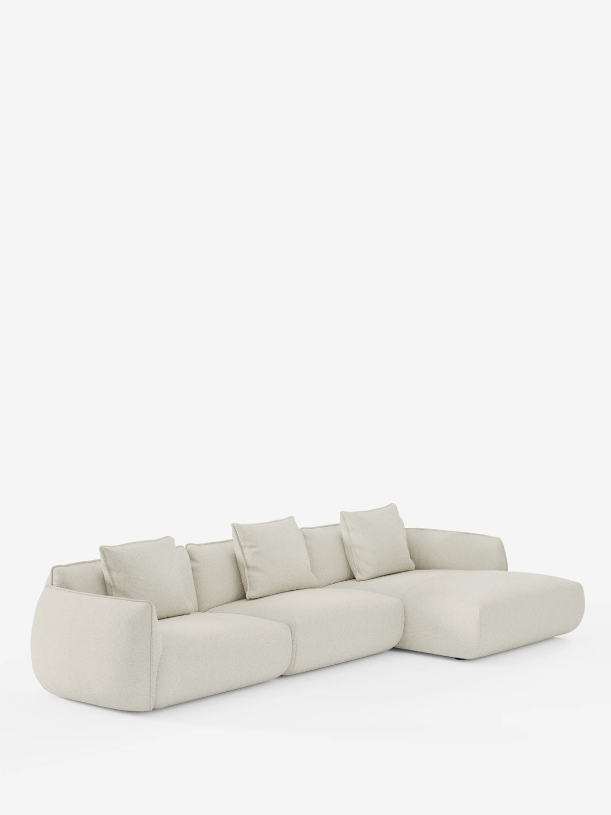 Il divano angolare con penisola componibile Nimbus di divitt.sbs è un divano moderno color beige chiaro, realizzato in morbido tessuto effetto cotone smacchiabile T33, con chaise longue sul lato destro. Questo modello dal design contemporaneo include quattro cuscini dello schienale coordinati e presenta una silhouette bassa, arrotondata e minimalista che risalta su uno sfondo bianco a tinta unita.