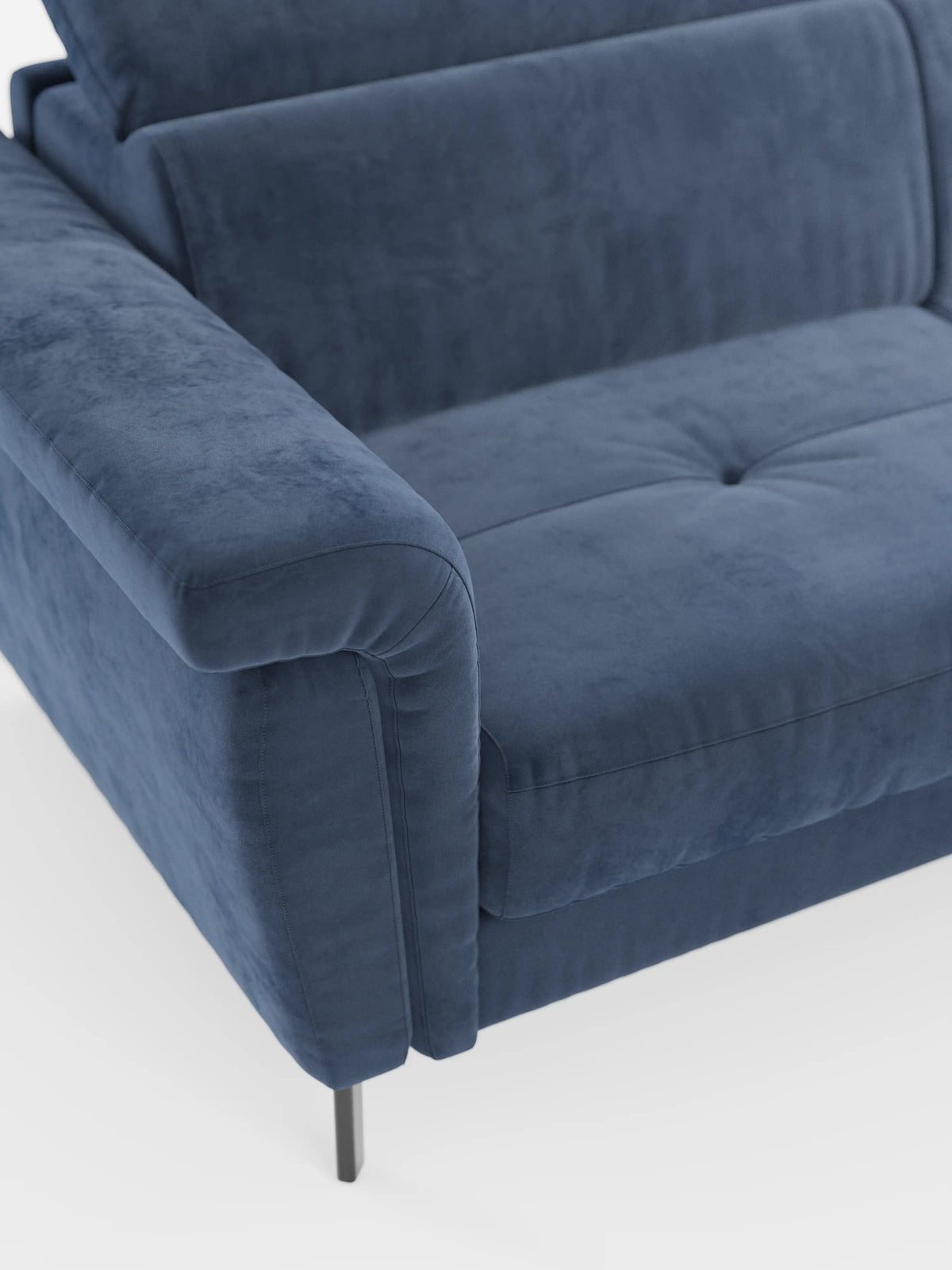 Un primo piano del divano letto di design Capri con piedini alti di divitt.sbs, rivestito in raffinato tessuto effetto velluto smacchiabile T30. Questo moderno divano blu effetto velluto è frutto della maestria artigianale italiana, con ampi braccioli, schienale imbottito, due sottili gambe in metallo nero e poggiatesta regolabili per un tocco di lusso in più, il tutto su uno sfondo bianco.