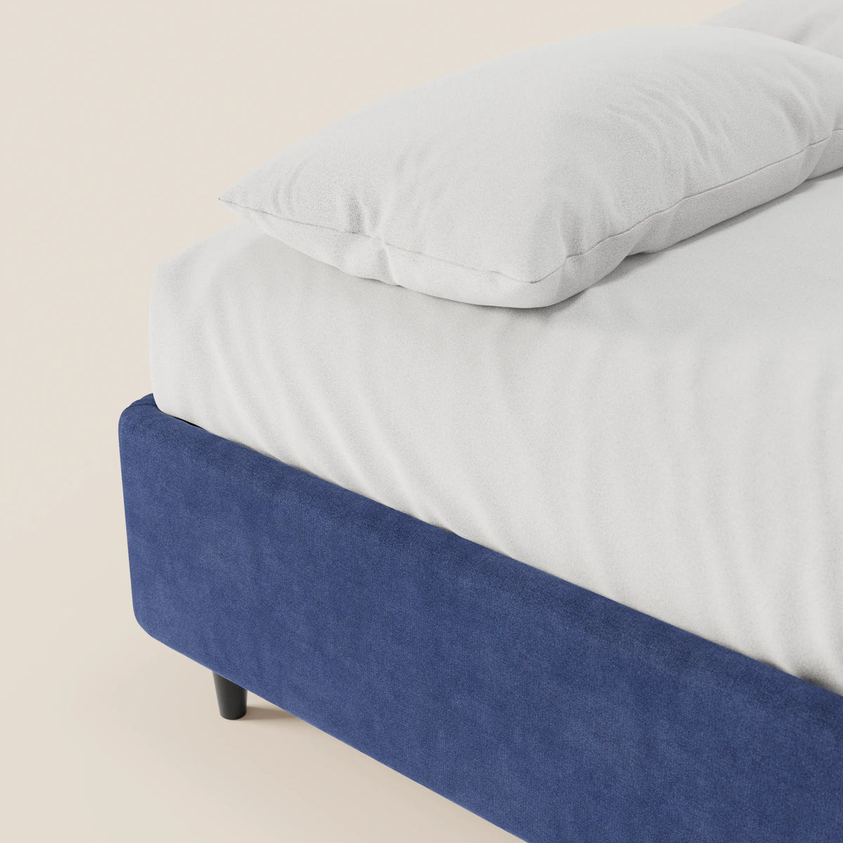 Un primo piano del letto sommier imbottito ERON di Letti.store mostra un letto ben rifatto con un cuscino bianco e un lenzuolo con angoli. La struttura in tessuto impermeabile blu scuro, certificata Oeko-Tex, risalta sullo sfondo beige, mettendo in risalto il design moderno.