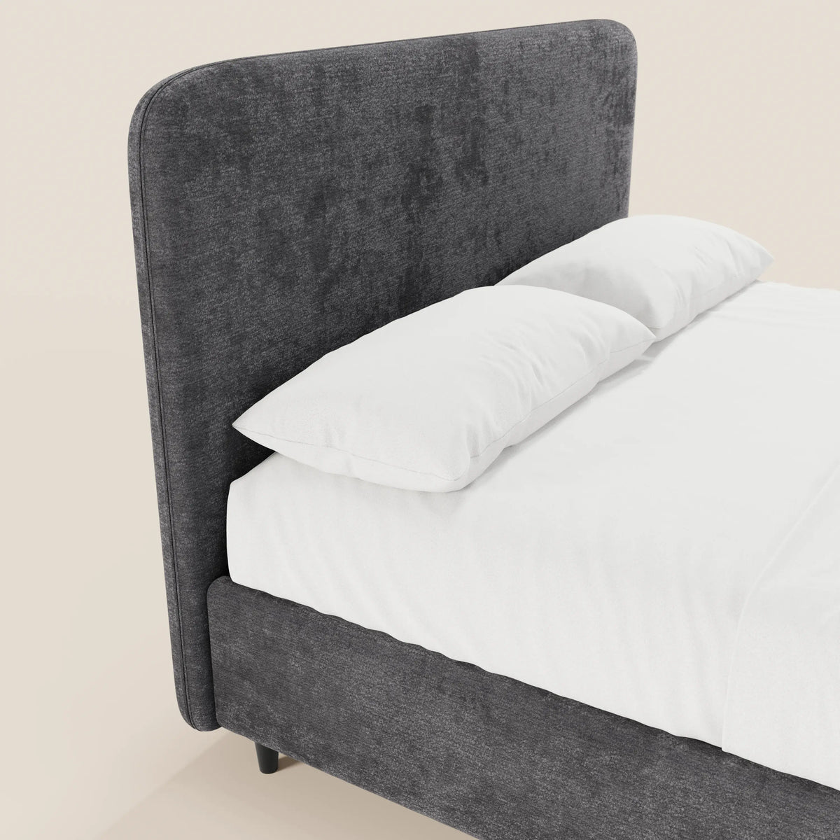 Il letto imbottito KAELOS minimal di Letti.store presenta una testiera alta e arrotondata in ciniglia e una struttura coordinata con gambe alte e vano contenitore, qui raffigurato in grigio antracite su uno sfondo crema chiaro, per un look pulito e minimalista, abbinato a lenzuola e cuscini di un bianco brillante.