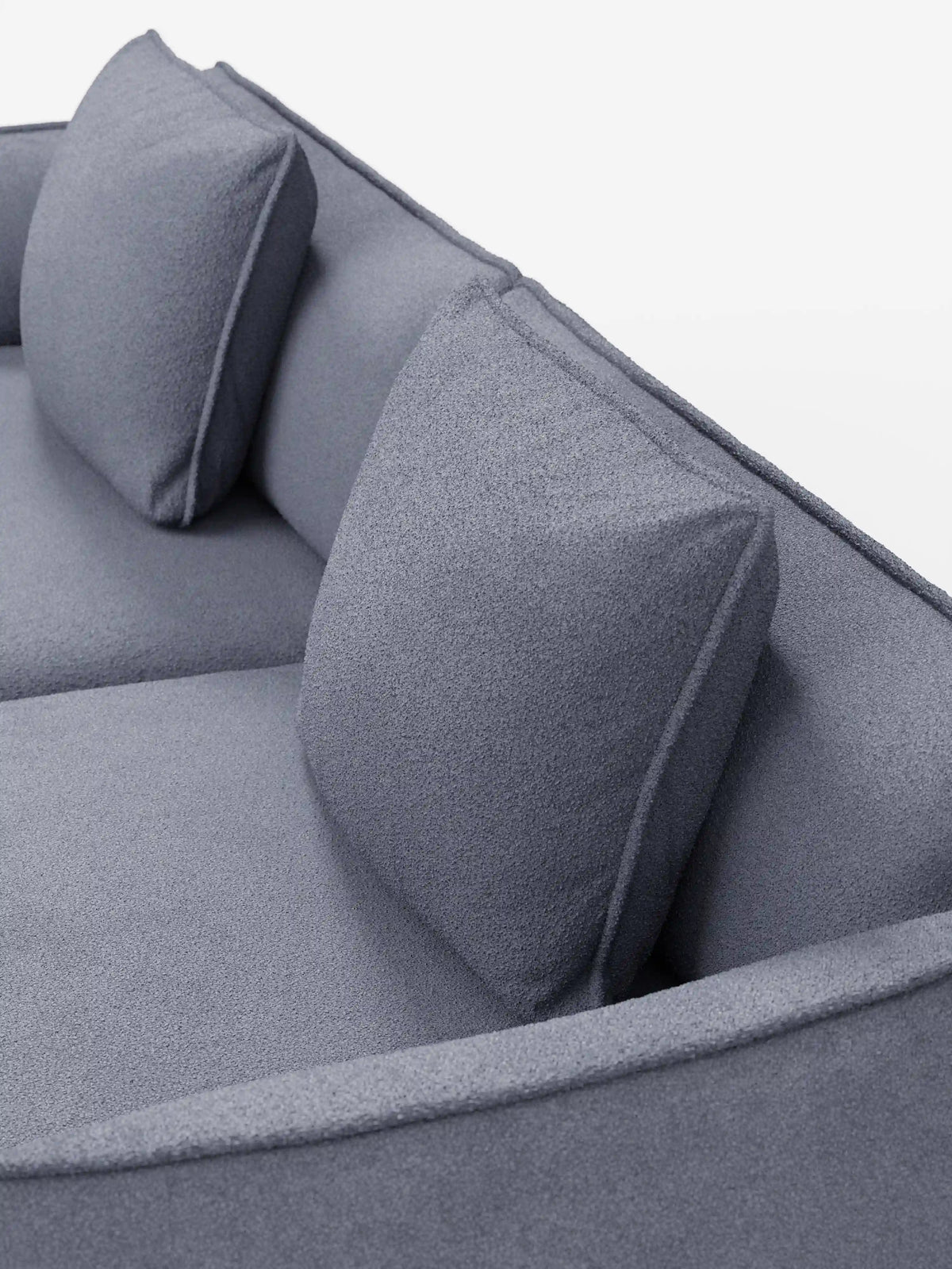 Un primo piano del divano modulare e componibile a 3 posti Nimbus di divitt.sbs, da 250 cm, presentato in un moderno tessuto effetto cotone di colore grigio chiaro resistente alle macchie (t33), caratterizzato da due cuscini dello schienale quadrati e braccioli arrotondati su uno sfondo bianco. Il rivestimento sfoderabile appare morbido, accentuando il design minimalista e contemporaneo del divano.