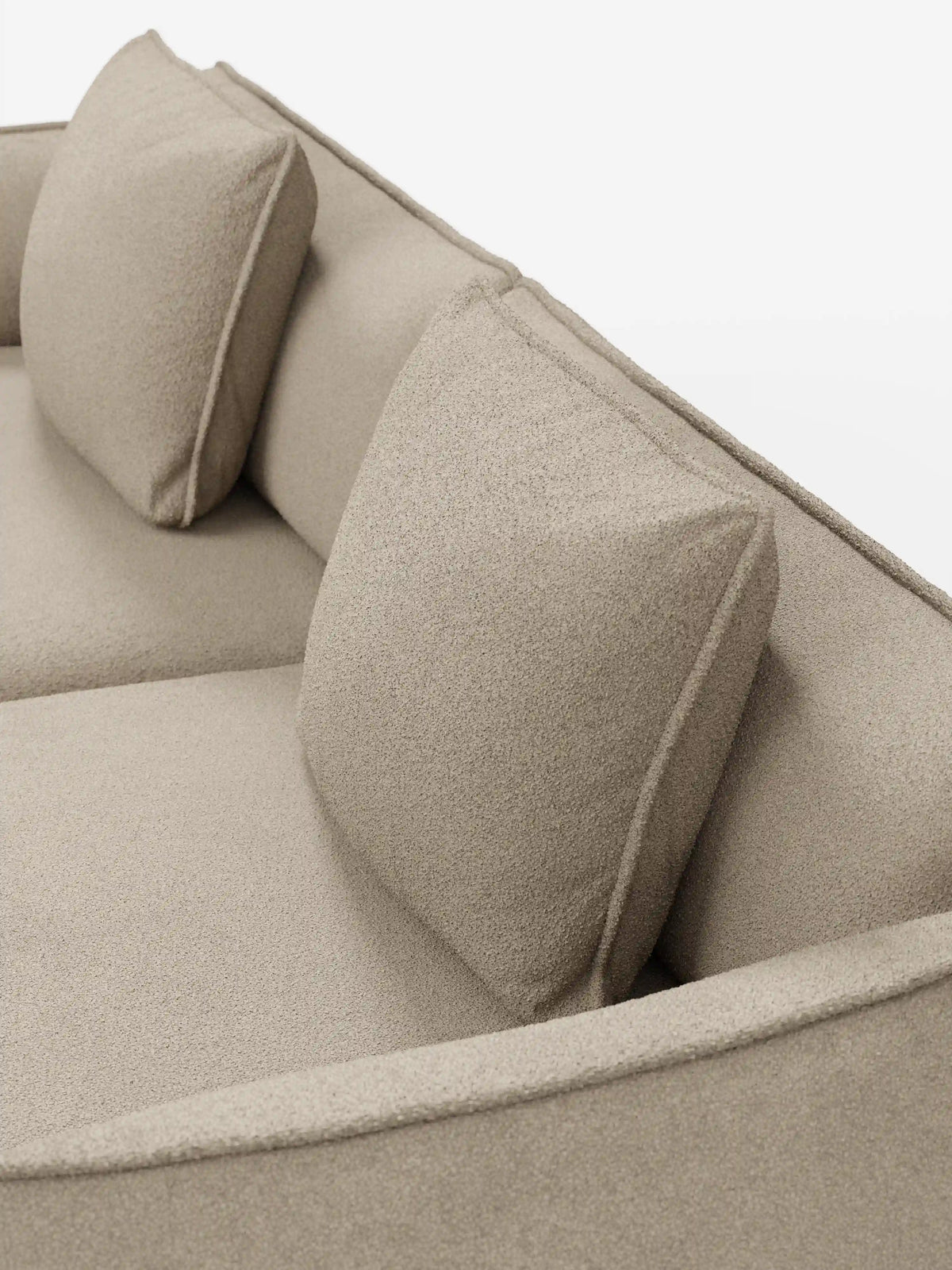 Primo piano del divano Nimbus a 3 posti, modulare e componibile da 250 cm di divitt.sbs, rivestito in tessuto effetto cotone beige (t33), sfoderabile e antimacchia. Il divano modulare presenta due cuscini schienali quadrati e una seduta liscia dall’aspetto morbido e strutturato. La foto è stata scattata da una prospettiva obliqua dall’alto su uno sfondo bianco a tinta unita.