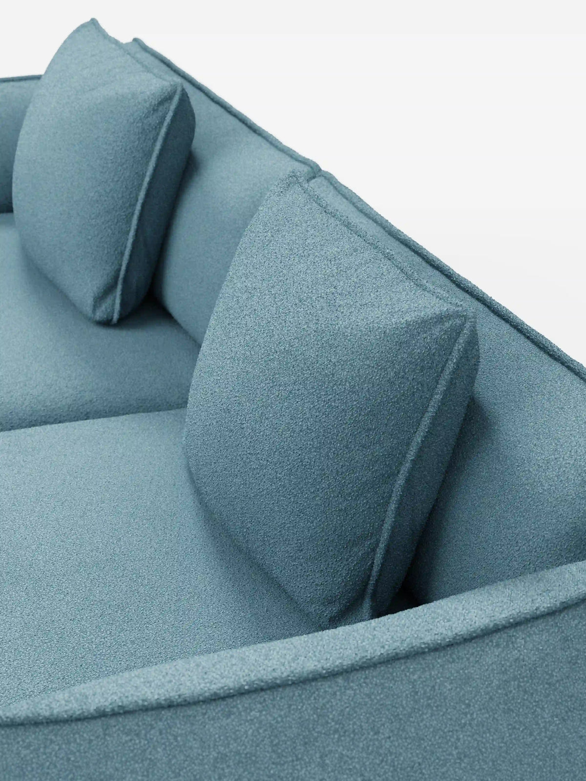 Primo piano del divano modulare e componibile Nimbus a 3 posti di divitt.sbs, qui presentato in tessuto T33 effetto cotone smacchiabile di colore azzurro. Questo divano moderno da 250 cm è caratterizzato da due cuscini dello schienale quadrati e da un rivestimento morbido e leggermente ruvido. I bordi puliti e arrotondati ne esaltano il design minimalista, mentre lo sfondo bianco a tinta unita mette in risalto il colore e lo stile contemporaneo del divano.