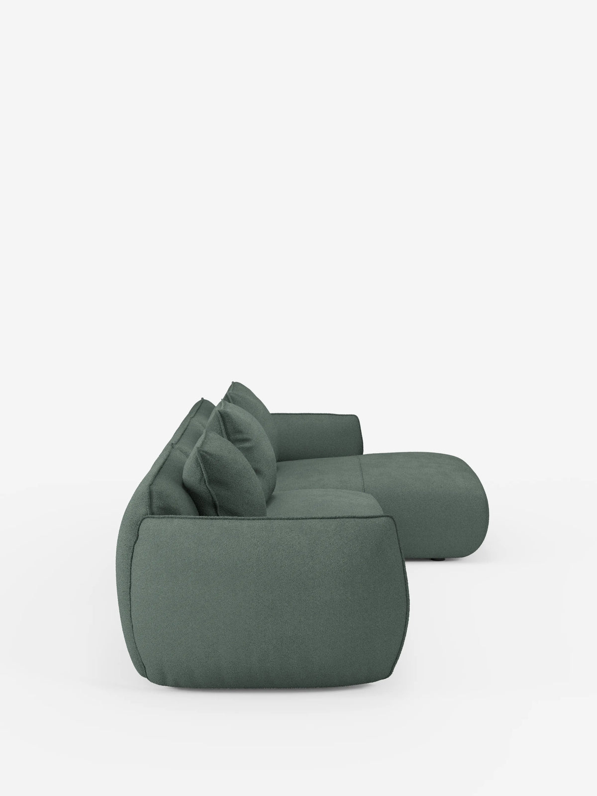 Il divano angolare con penisola componibile Nimbus di divitt.sbs è raffigurato di profilo su uno sfondo bianco a tinta unita. Questo moderno divano modulare verde, realizzato in morbido tessuto T33 effetto cotone resistente alle macchie, presenta un profilo basso e lussuoso con cuscini spessi e bordi arrotondati che gli conferiscono un aspetto morbido e accogliente. Il design comprende tre cuscini dello schienale e ampi braccioli.