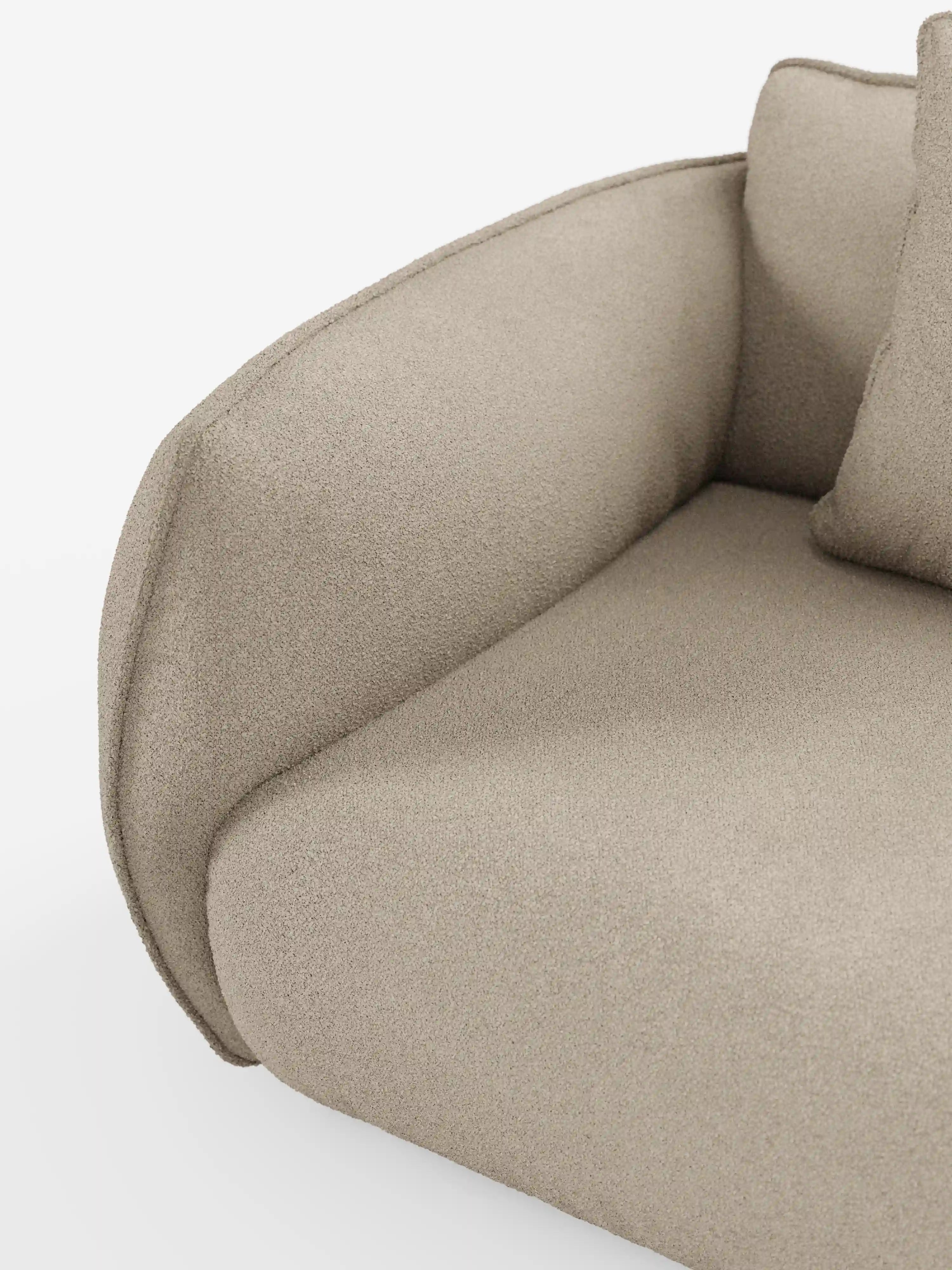 Primo piano del divano modulare a 3 posti “Nimbus” di divitt.sbs, realizzato in tessuto T33 beige, con effetto cotone, testurizzato e resistente alle macchie, che mette in risalto il bracciolo ricurvo, il cuscino di seduta e parte del cuscino dello schienale. Il design minimalista e moderno è caratterizzato da linee pulite, con uno sfondo bianco a tinta unita che mette in risalto la silhouette e il materiale del divano.