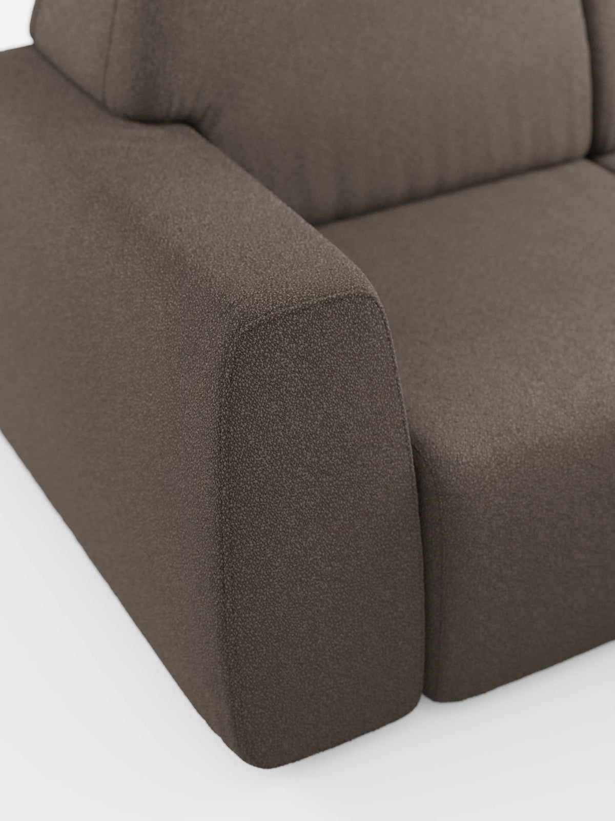 Primo piano del divano angolare Orbit con penisola reversibile e tutte le sedute allungabili in tessuto smacchiabile effetto cotone T33 di divitt.sbs, che mette in risalto l'angolo imbottito marrone con bracciolo a vista, cuscino di seduta e parte dello schienale. Il tessuto antimacchia effetto cotone presenta un aspetto raffinato e strutturato su uno sfondo bianco. Questo divano modulare vanta un design moderno dalle linee pulite e spigolose che esaltano la maestria artigianale e lo stile di alta gamma.