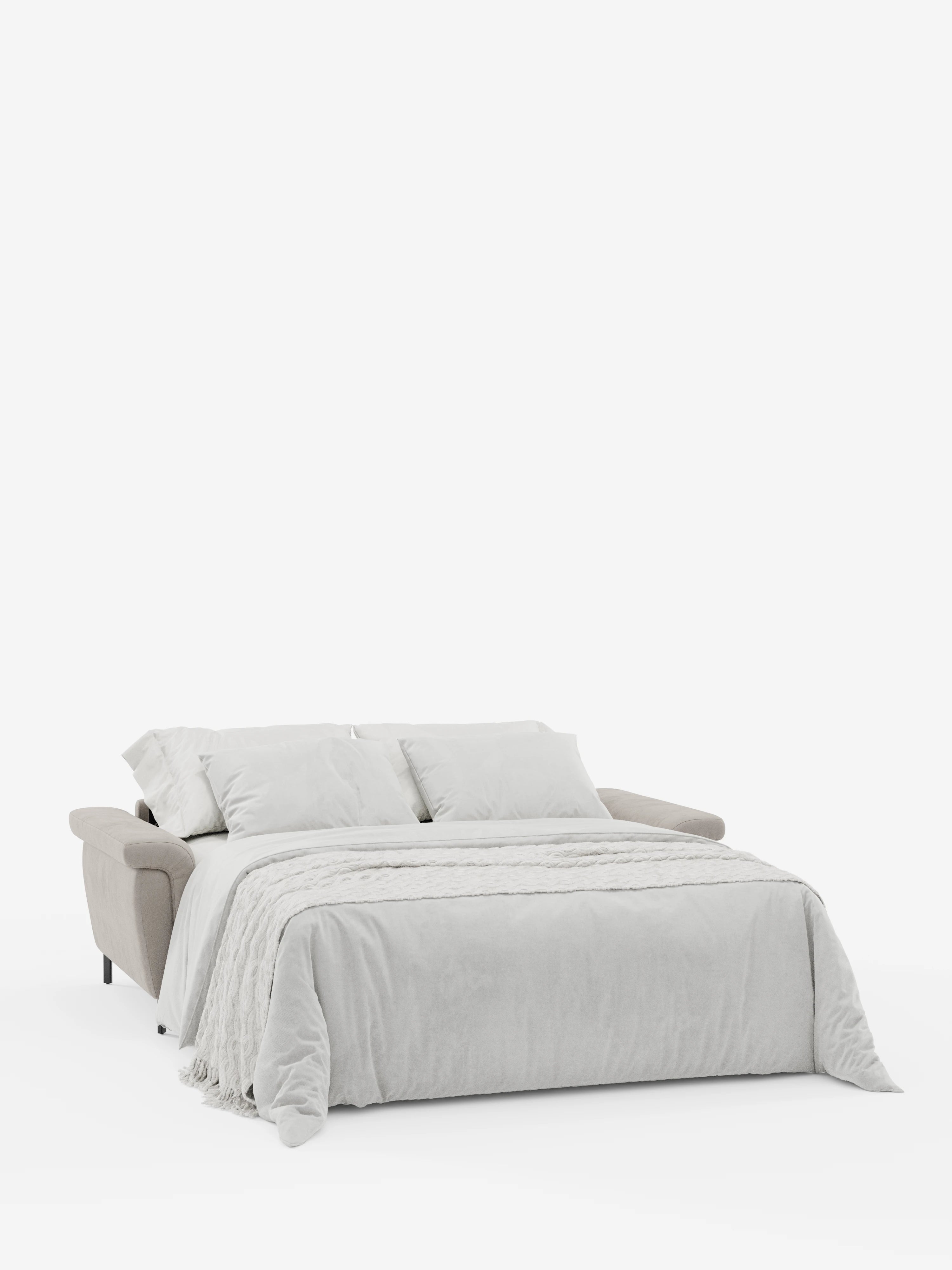 Un divano letto di design Capri color beige con piedini alti e poggiatesta reclinabili di divitt.sbs è aperto in modalità letto, rivestito con biancheria da letto grigio chiaro e completato da due morbidi cuscini e una coperta. Lo sfondo bianco mette in risalto il design moderno e lineare, nonché le morbide trame del raffinato tessuto effetto velluto smacchiabile T30 del divano.