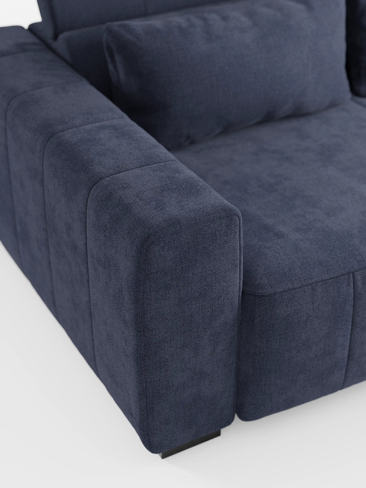 Primo piano del divano a 3 posti Doric di divitt.sbs, caratterizzato da un moderno rivestimento in tessuto T23 blu navy resistente alle macchie, morbidi cuscini coordinati, braccioli rettangolari e un poggiatesta reclinabile. Di questo divano contemporaneo con sedute reclinabili elettriche è visibile solo un angolo, su uno sfondo bianco.