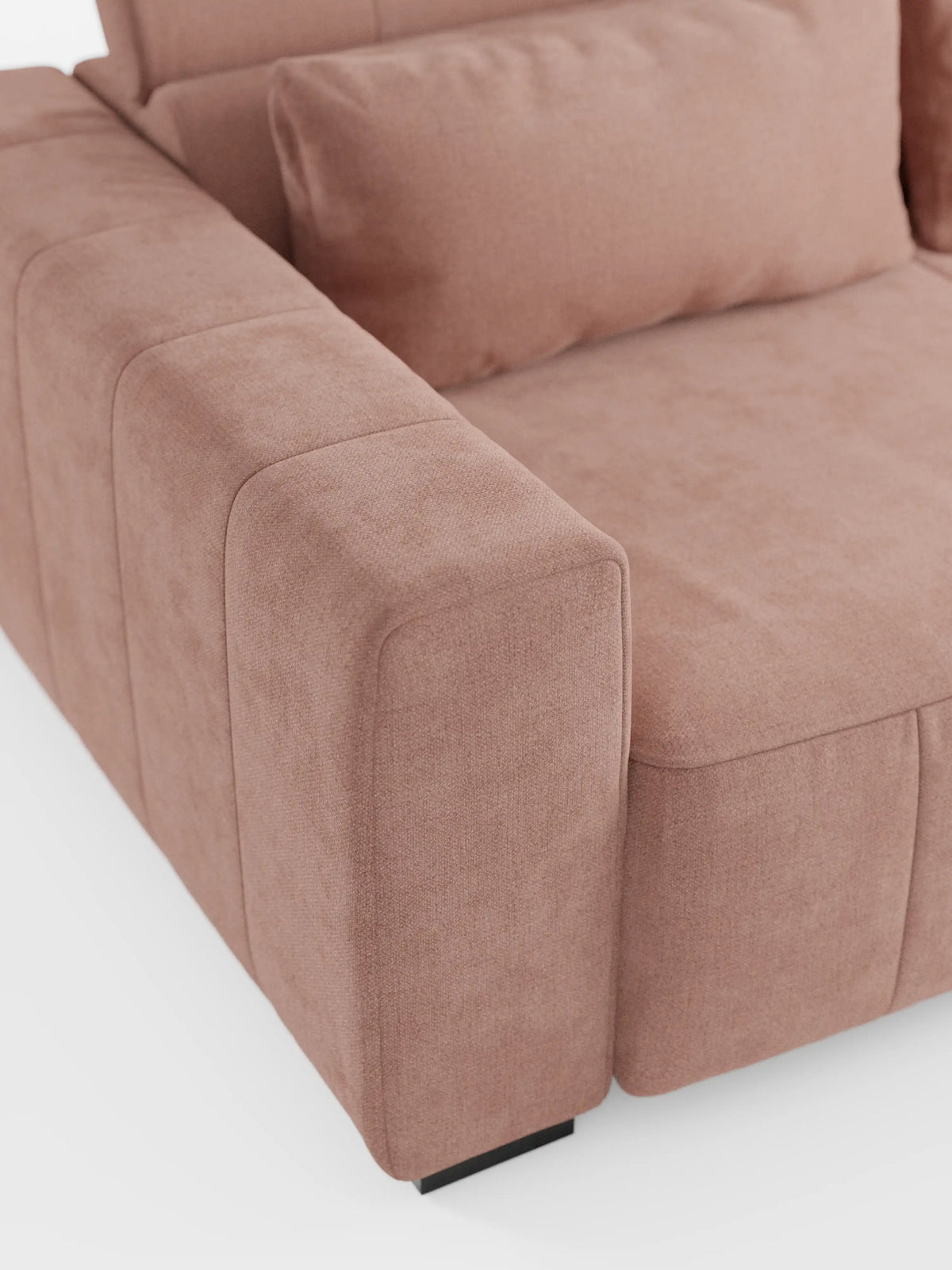 Primo piano del divano a 3 posti Doric di divitt.sbs, caratterizzato da un design moderno e rivestito in morbido tessuto T23 smacchiabile color rosa cipria. L'immagine mette in risalto i morbidi cuscini dei braccioli e della seduta, con un cuscino coordinato appoggiato allo schienale reclinabile. Sullo sfondo bianco, la struttura sfoderabile del divano, le linee pulite e le sedute estensibili con funzione relax elettrica sono messe in risalto nei minimi dettagli.