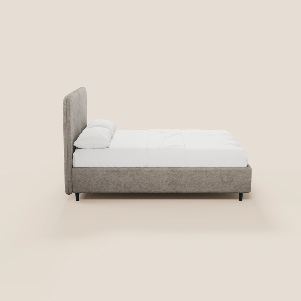 Vista laterale del letto KAELOS minimal imbottito di Letti.store, caratterizzato da una struttura rivestita in ciniglia grigio chiaro, una testiera alta e arrotondata, gambe alte e una base con contenitore. Il letto è rifatto con cura, con biancheria da letto bianca su uno sfondo beige crema.