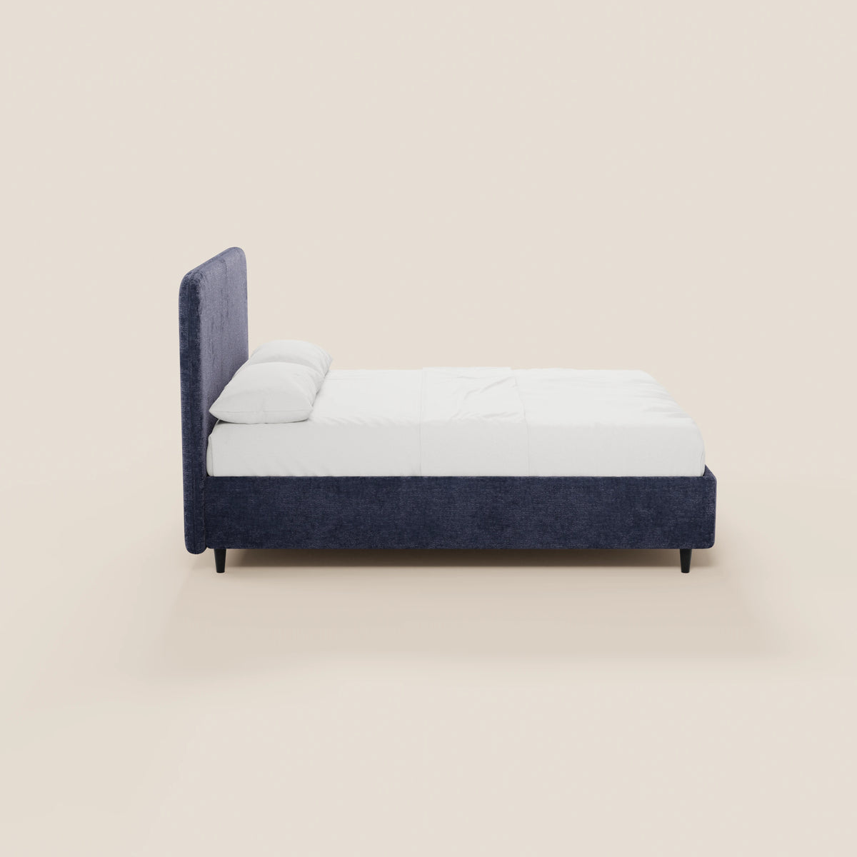 Il letto KAELOS minimal imbottito di Letti.store presenta una struttura rivestita in ciniglia blu scuro con testiera imbottita ad arco, biancheria da letto bianca, due cuscini, gambe alte nere e un vano contenitore, raffigurato di profilo su uno sfondo beige chiaro.