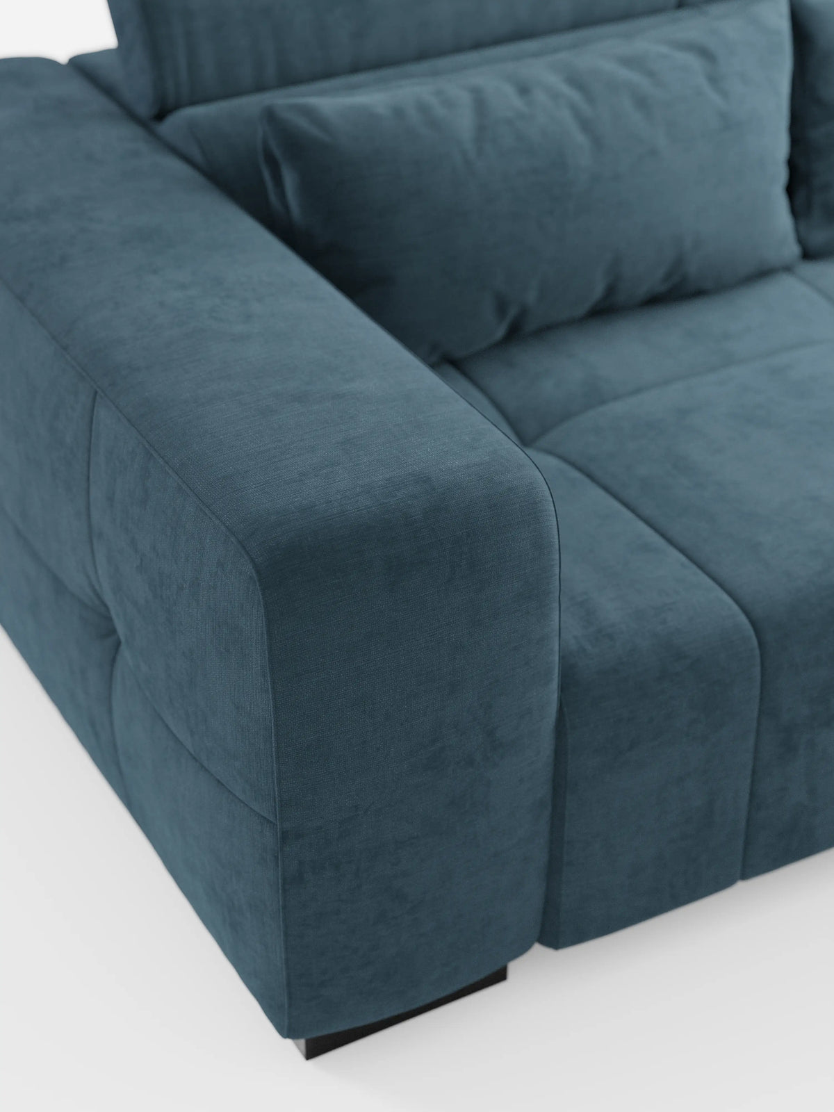 Primo piano del divano Monarch con funzione relax elettrica per l’allungamento delle sedute e poggiatesta reclinabile, rivestito in morbido tessuto smacchiabile T31 di divitt.sbs, che mette in risalto il suo moderno rivestimento in velluto blu-verde acqua, i braccioli generosi e il cuscino imbottito. Questo divano contemporaneo presenta una silhouette squadrata e lussuosa con cuciture a vista e poggia su gambe corte nere su uno sfondo bianco a tinta unita.