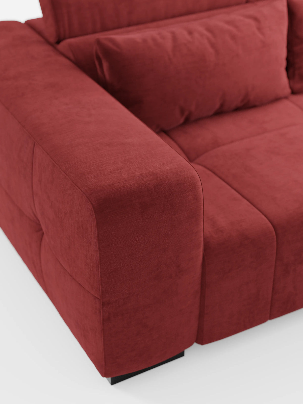Un primo piano del divano Monarch con funzione relax elettrica per l’allungamento delle sedute e poggiatesta reclinabile di divitt.sbs, rivestito in tessuto T31 rosso intenso, morbido e resistente alle macchie. L'immagine mette in risalto gli ampi braccioli, la seduta e il cuscino dello schienale, esaltandone la consistenza morbida e le linee pulite e minimaliste. Il divano poggia su corte gambe rettangolari nere su uno sfondo bianco.