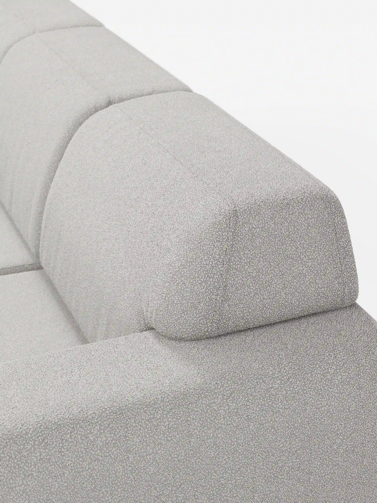 Primo piano del divano angolare Orbit con penisola reversibile e tutte le sedute allungabili in tessuto smacchiabile effetto cotone T33 di divitt.sbs, caratterizzato da un moderno schienale imbottito grigio chiaro dalle linee pulite e da un cuscino poggiatesta rettangolare angolare. Il tessuto antimacchia effetto cotone presenta una texture delicatamente ruvida, mentre il design minimalista risalta sullo sfondo bianco a tinta unita.
