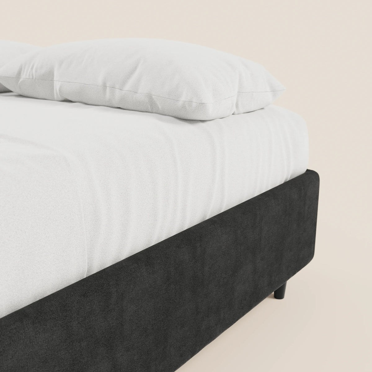 Un primo piano del letto sommier imbottito con contenitore ERON di Letti.store, realizzato con tessuto impermeabile certificato Oeko-Tex. Su una parete chiara si intravedono solo l’angolo del materasso e un cuscino bianco.