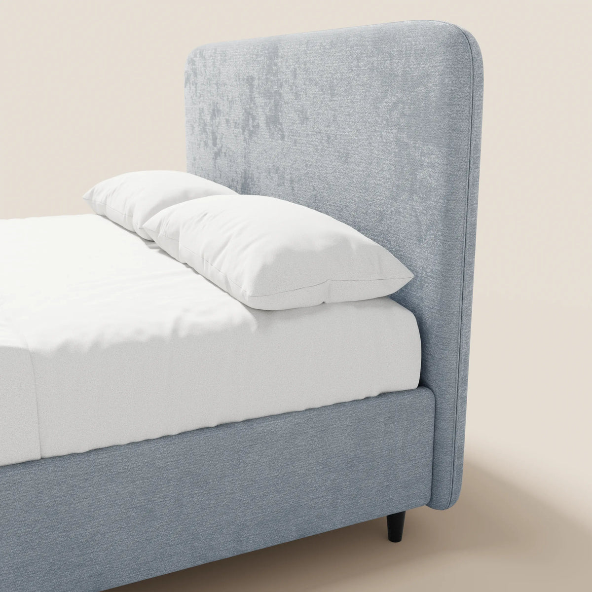 Il letto imbottito KAELOS minimal di Letti.store presenta una struttura rivestita in ciniglia azzurra e una testiera alta e arrotondata, lenzuola bianche, due cuscini bianchi e poggia su corte gambe nere su uno sfondo bianco sporco.